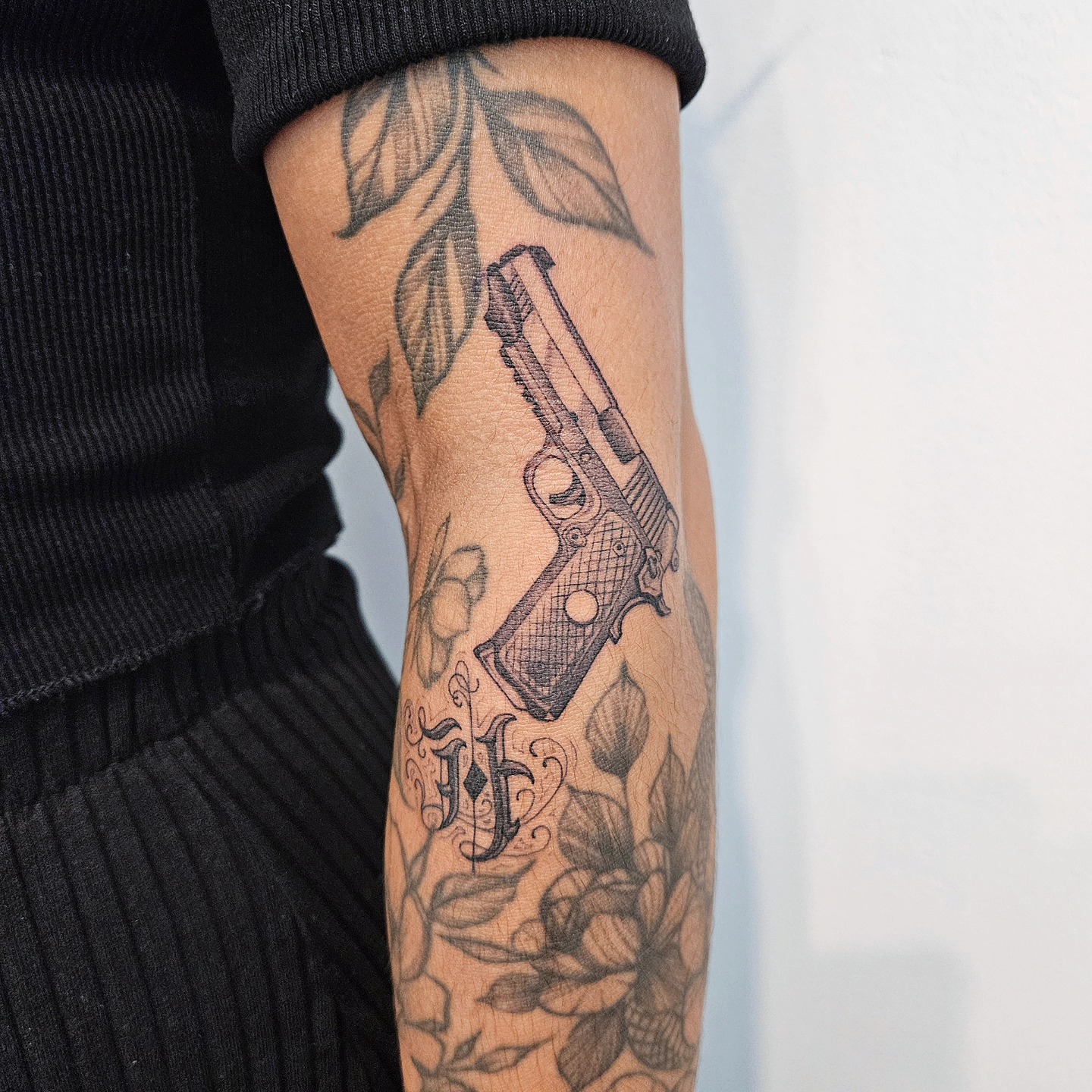 Gun and floral black and grey tattoo on the forearm by Tattooer Hermin 허민
