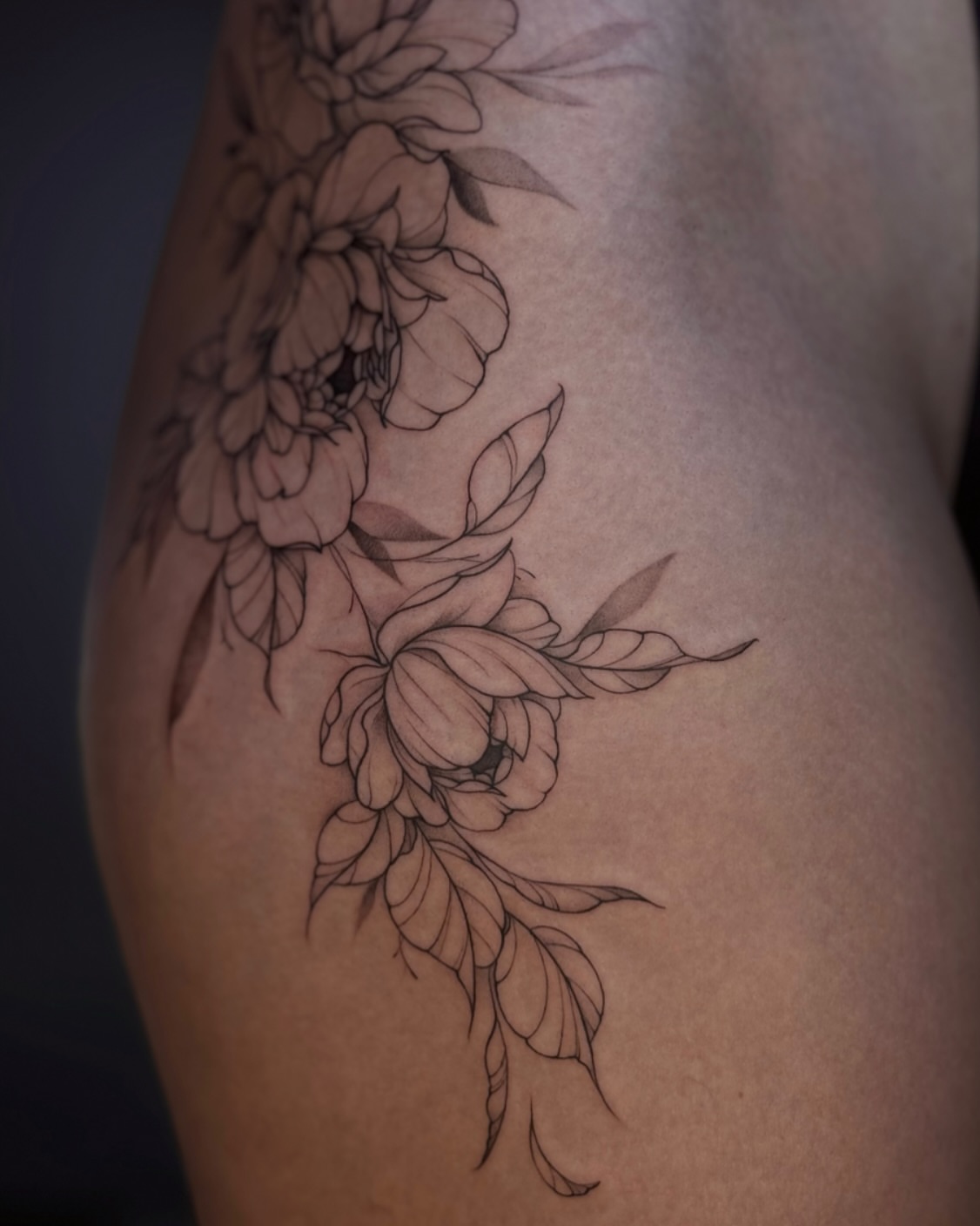 Floral arrangement black and grey tattoo on the thigh by Daria