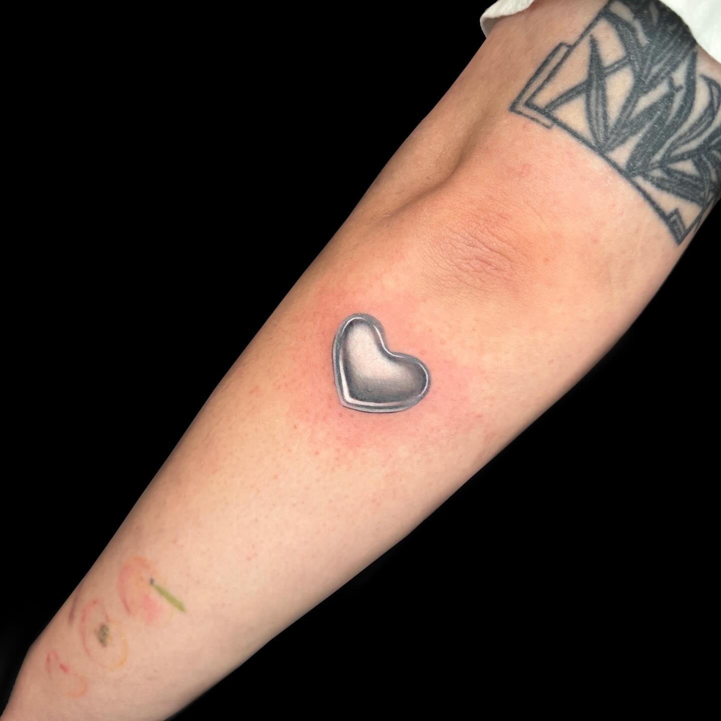Heart black and grey tattoo on the forearm by Mel