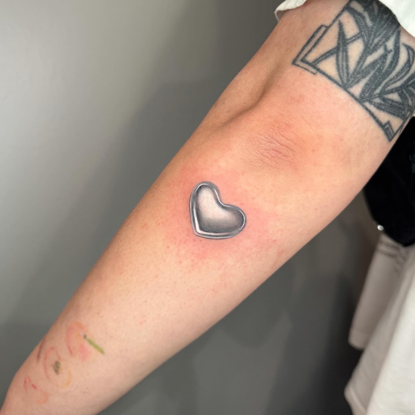 Heart black and grey tattoo on the forearm by Mel