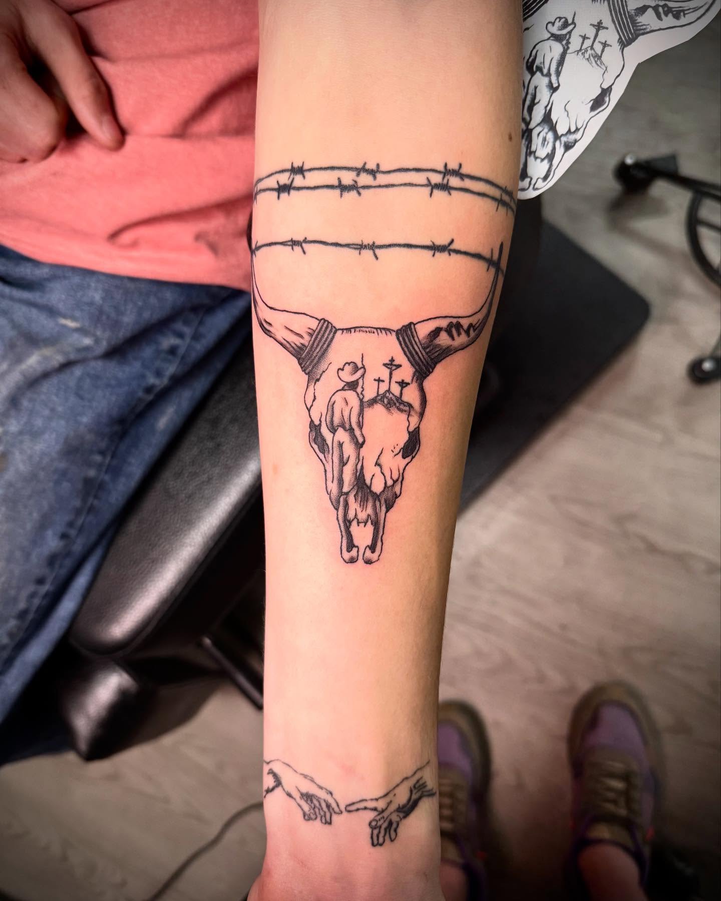 Cow skull with barbed wire black and grey tattoo on the forearm by Erick