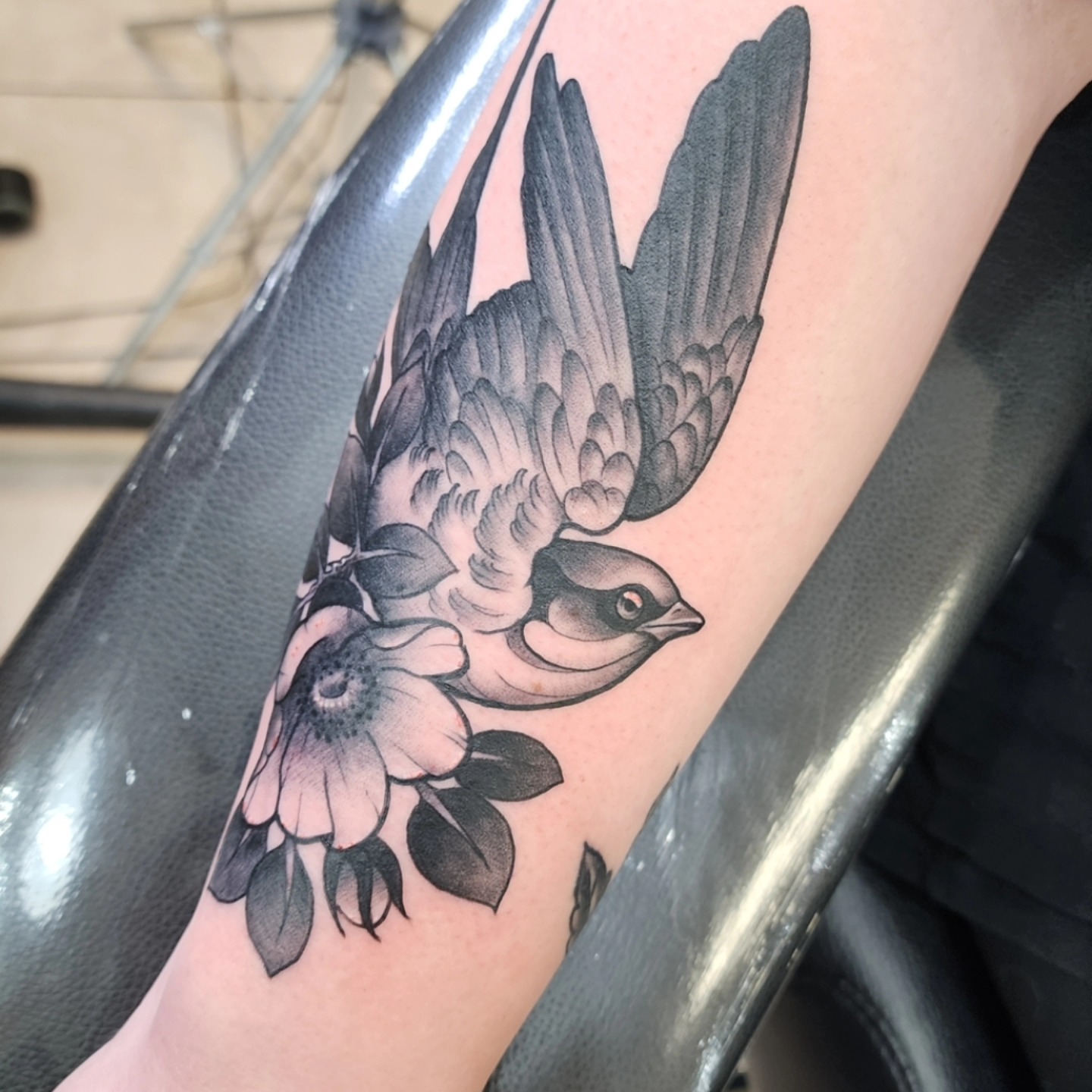 Swallow and flower black and grey tattoo on the forearm by bobby allensworth