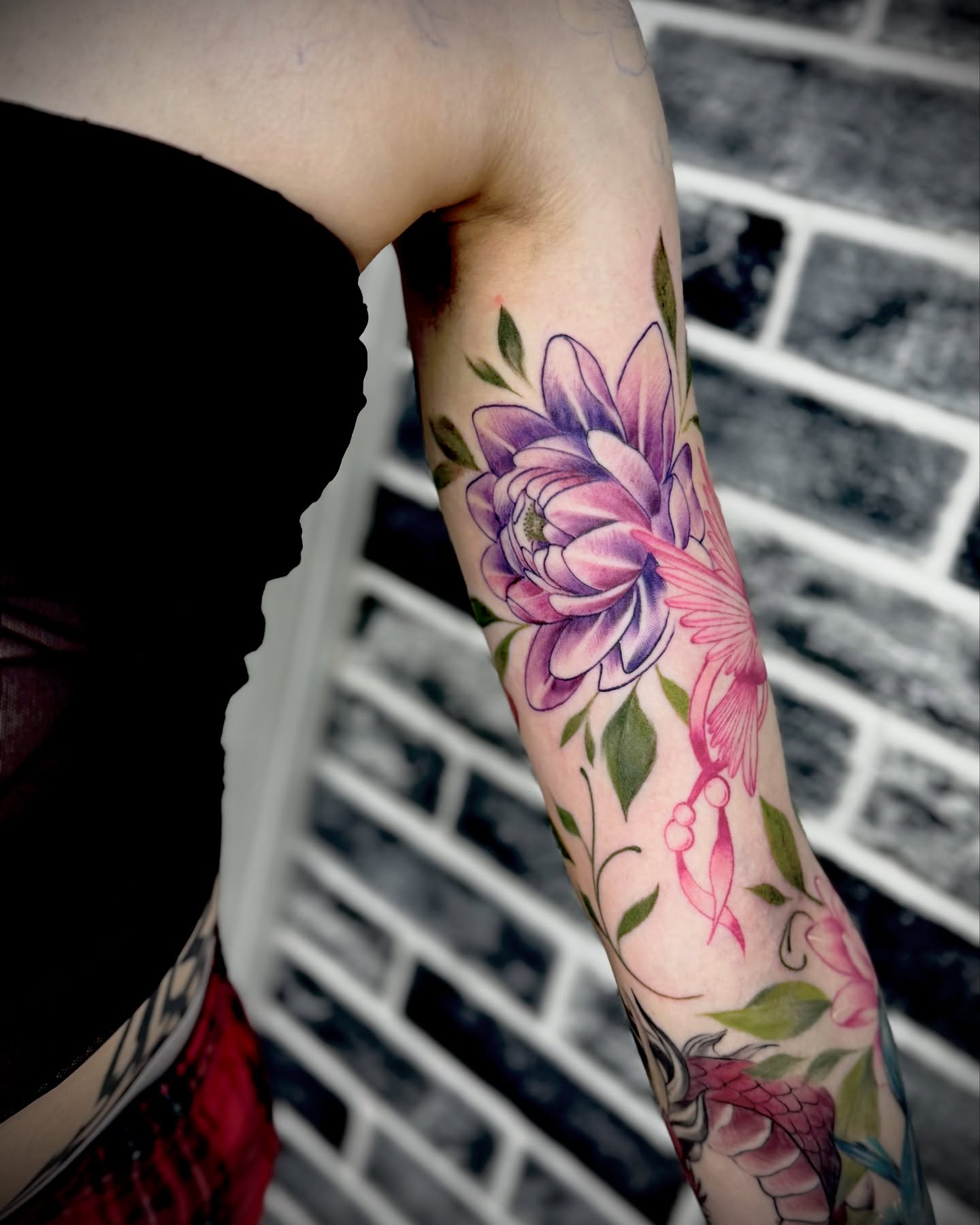 Flower and ribbon watercolor tattoo on the forearm by Mitsuko Ching