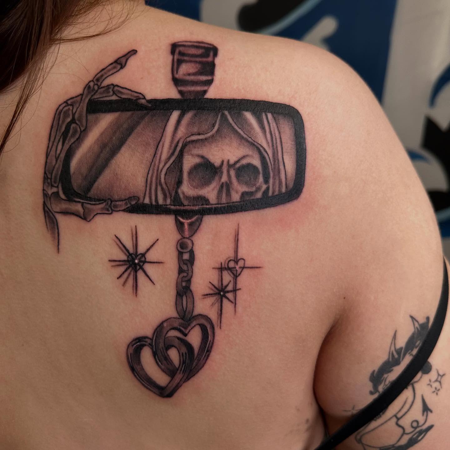 Rearview mirror with skull black and grey tattoo on the back by Kimberly landin