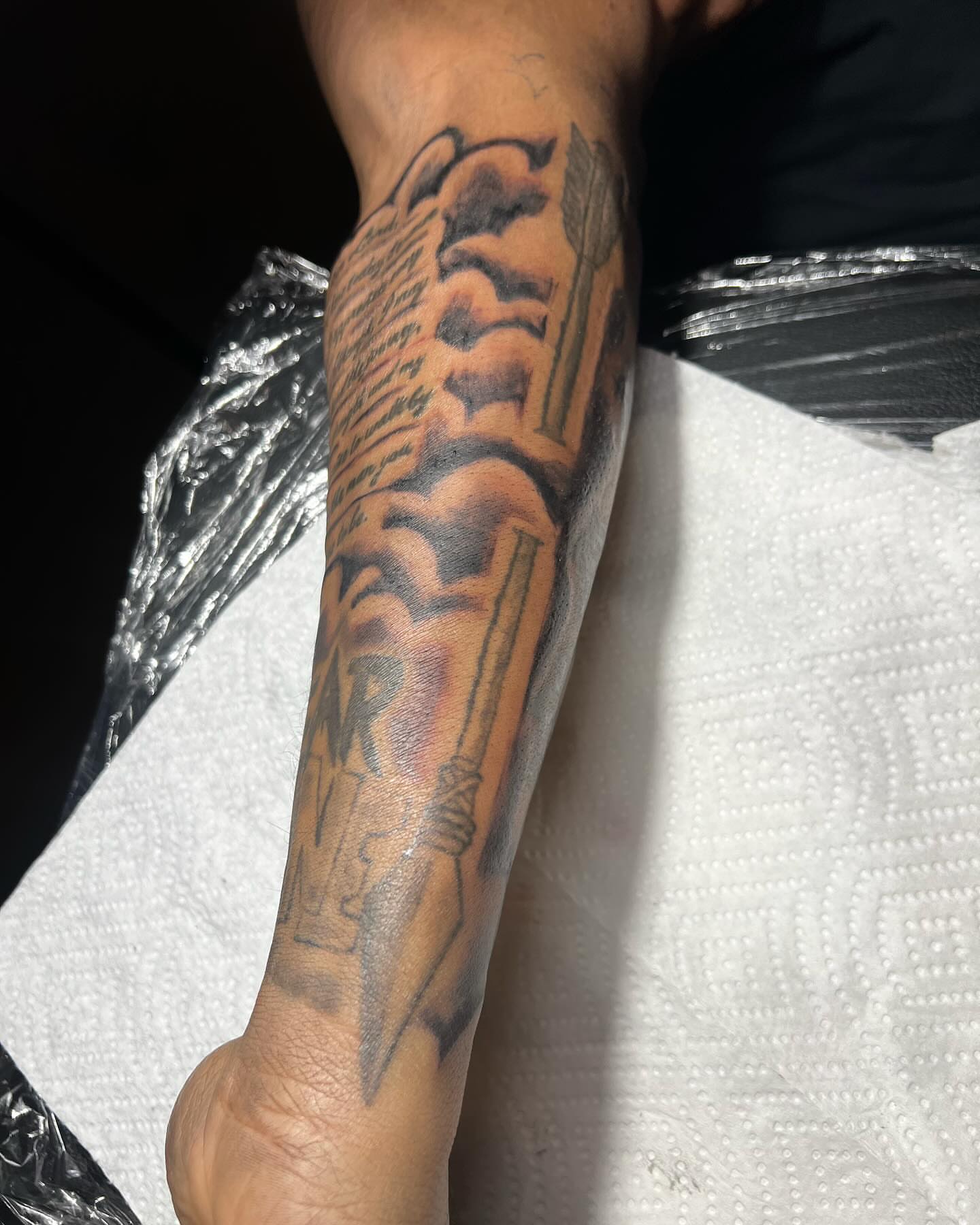 Script lettering black and grey tattoo on the forearm by Illuminink.gallery