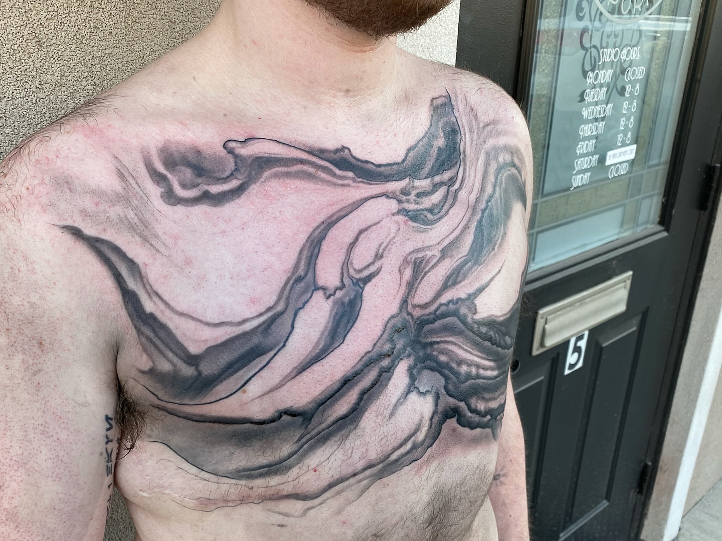Abstract fluid black and grey tattoo on the chest by Jake Kirk