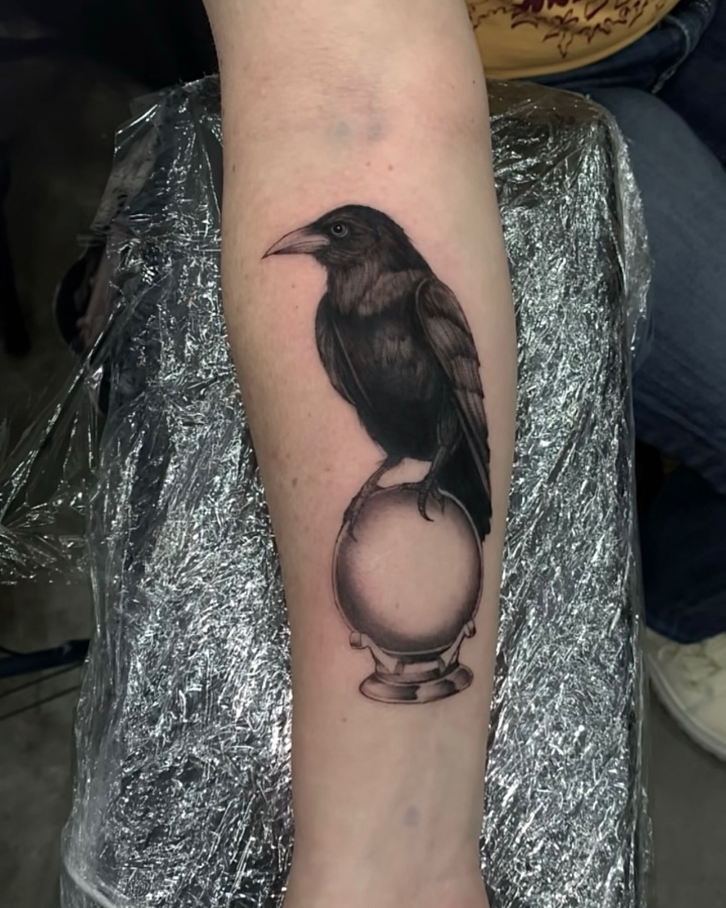 Crow and crystal ball realism tattoo on the forearm by Turk