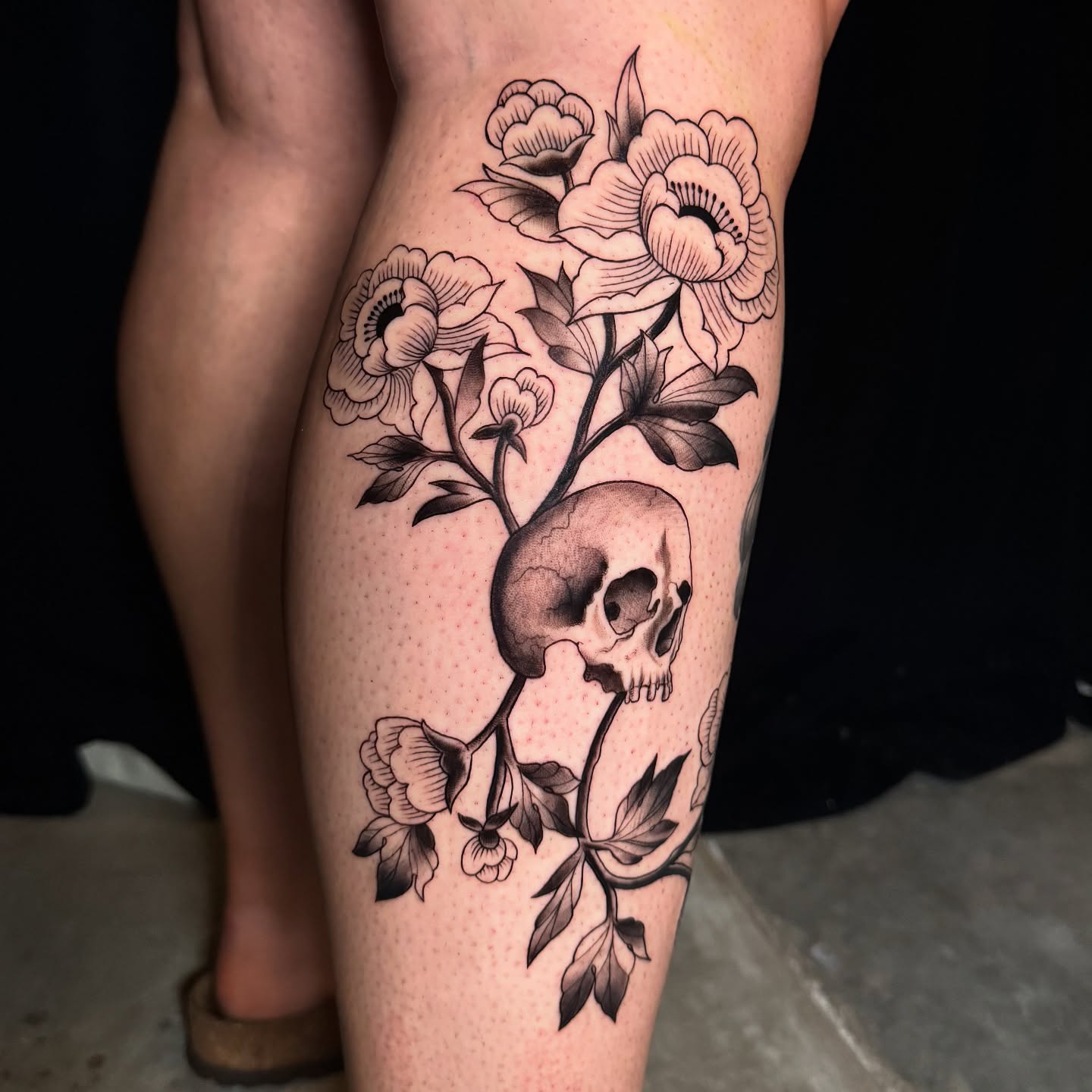 Skull and flowers dotwork tattoo on the thigh by Tori Bent
