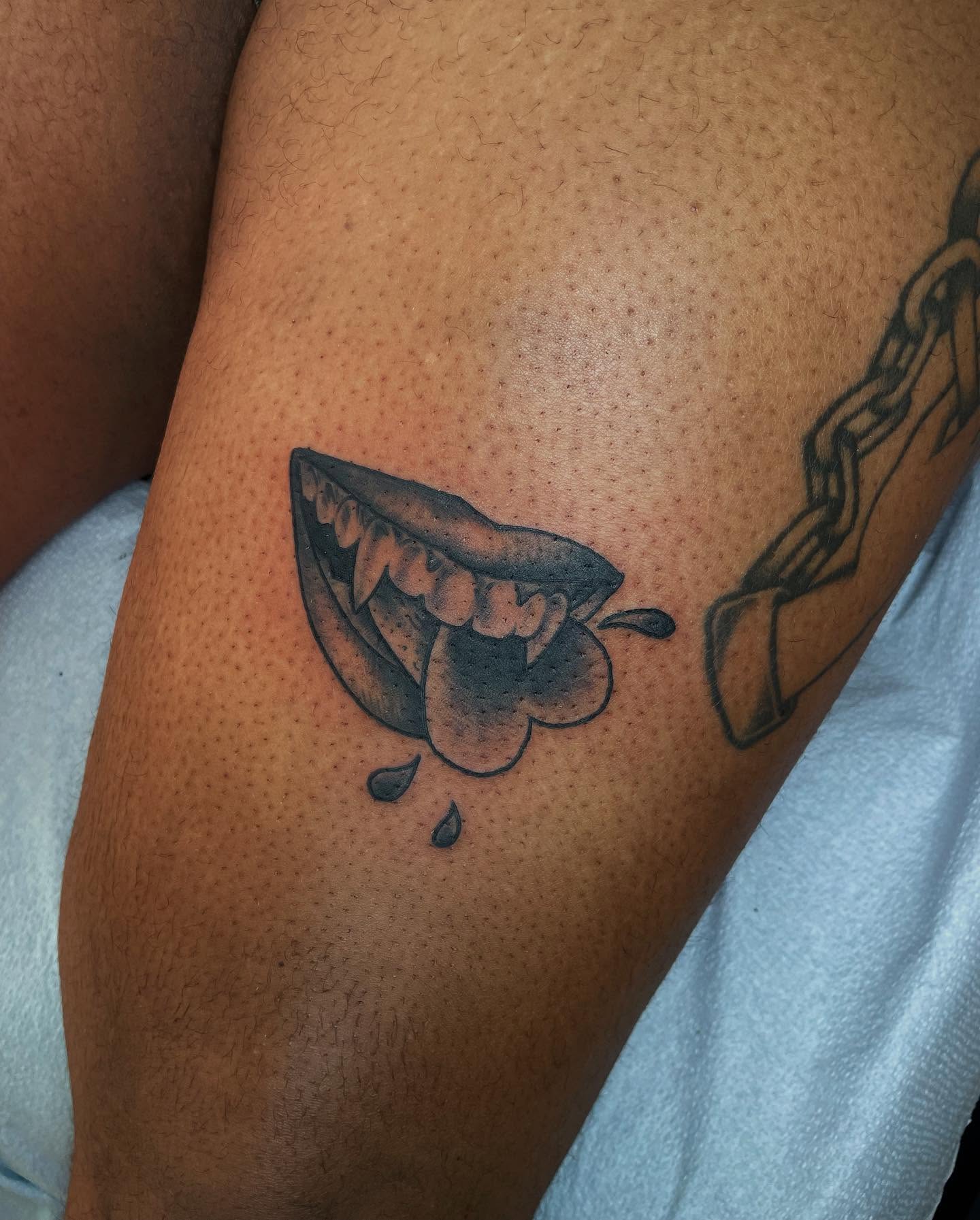 Fangs and chain black and grey tattoo on the thigh by G. Clover ⚧︎, Chicago, Illinois