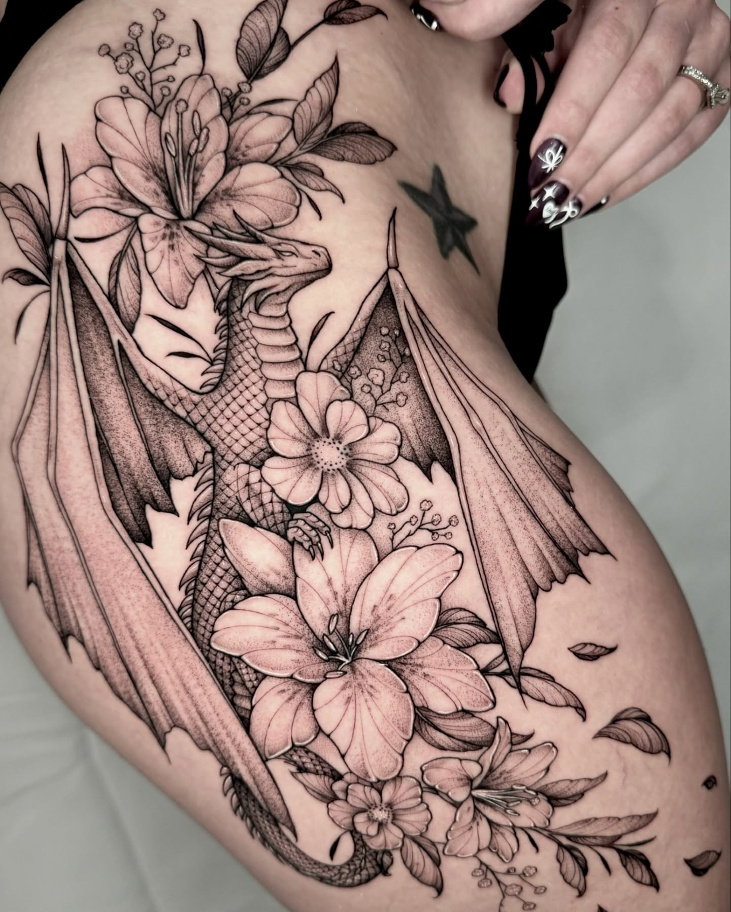 Dragon and floral bouquet realism tattoo on the thigh by Kathryn Semus
