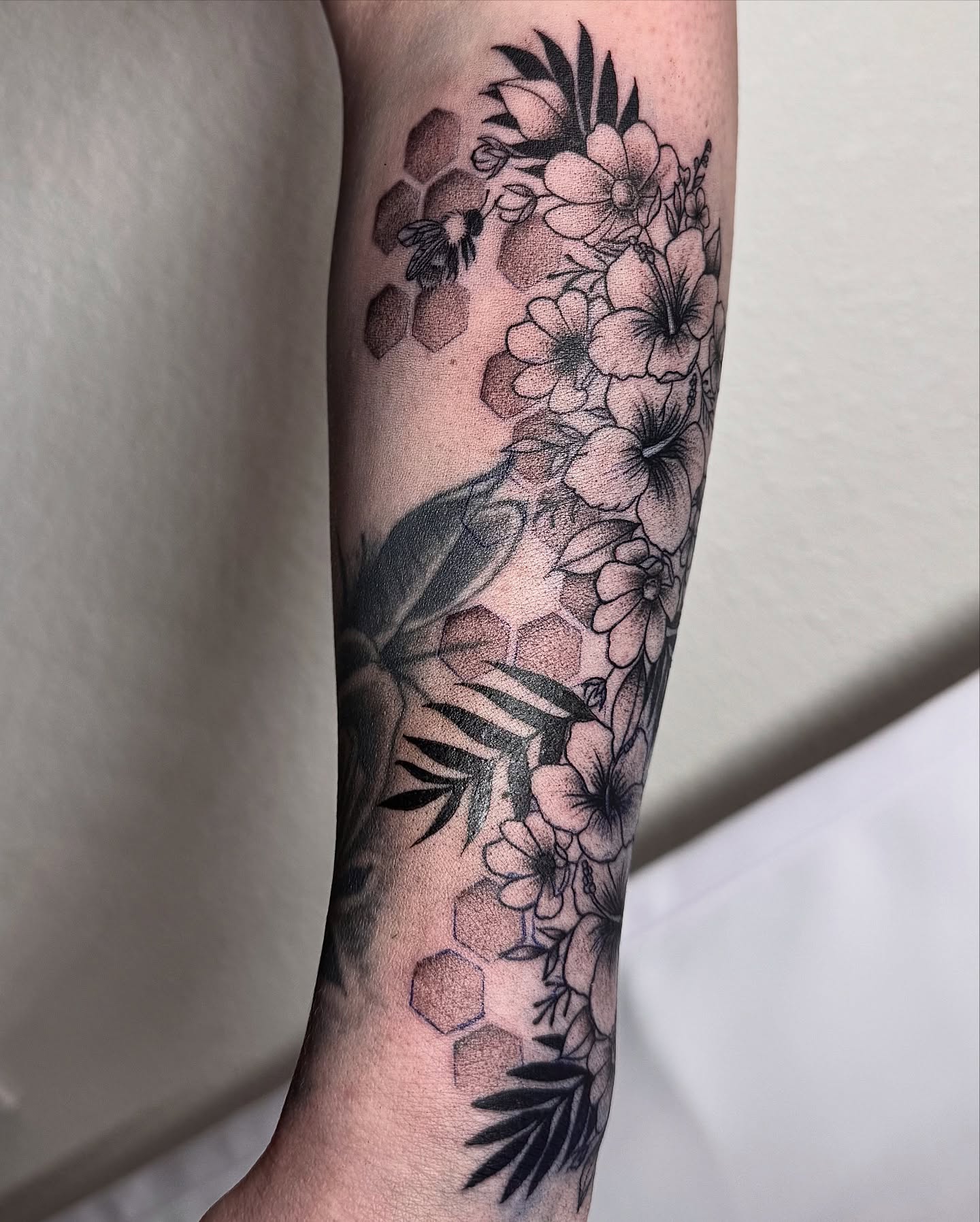 Bird and flowers black and grey tattoo on the forearm by Jess