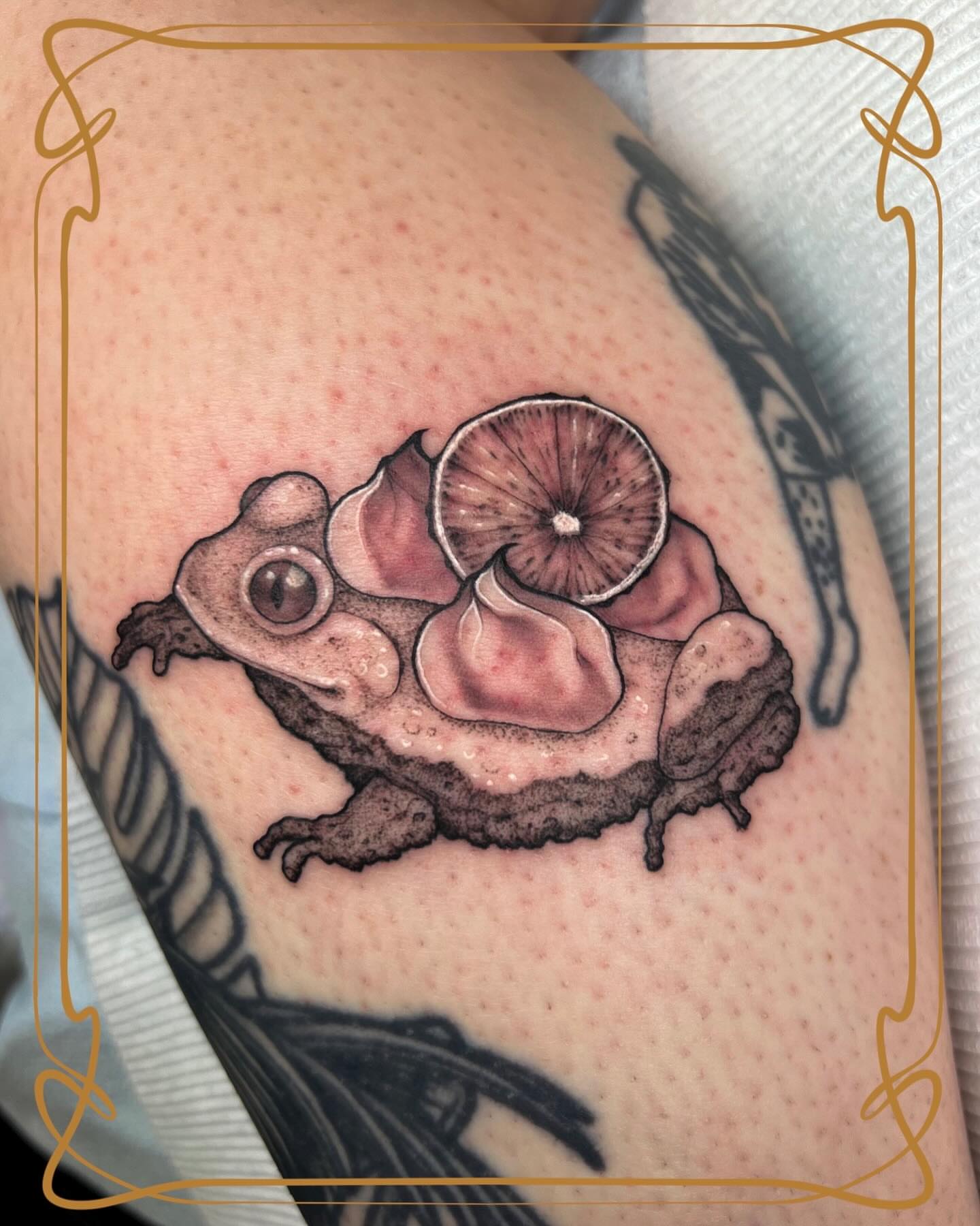 Frog with lemon slice realism tattoo on the thigh by Severin Black