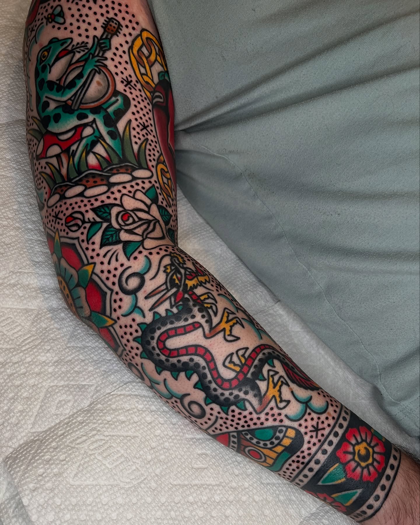 Serpent and floral motifs American traditional tattoo on the forearm by Ian Jett