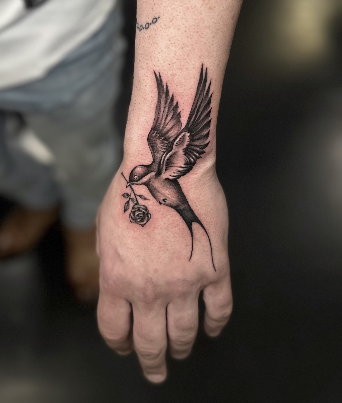Bird with rose realism tattoo on the hand by Madeleine Fleming
