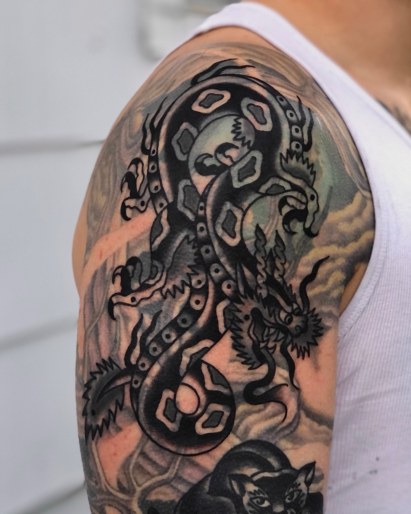 Serpent black and grey tattoo on the upper arm by EVA Traditional Tattoos