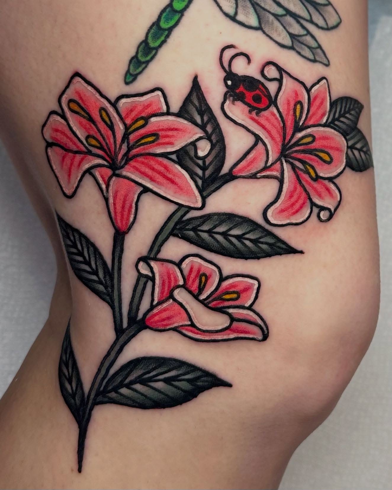 Lilies and ladybug American traditional tattoo on the forearm by rachel knabe