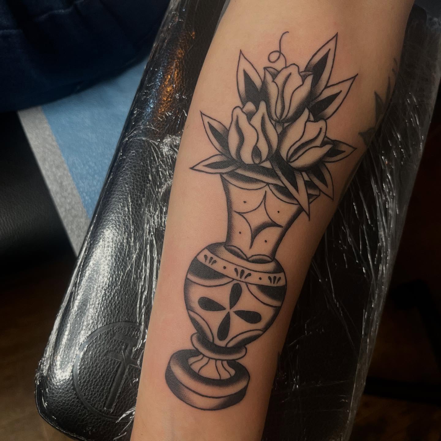 Flowers in vase black and grey tattoo on the forearm by Mariah Nguyen
