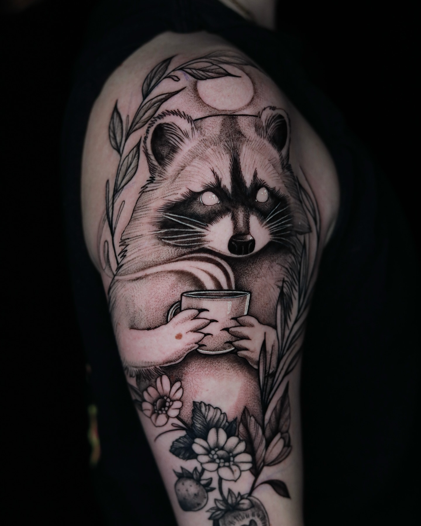 Raccoon holding mug realism tattoo on the upper arm by Jules, Arlington, Texas