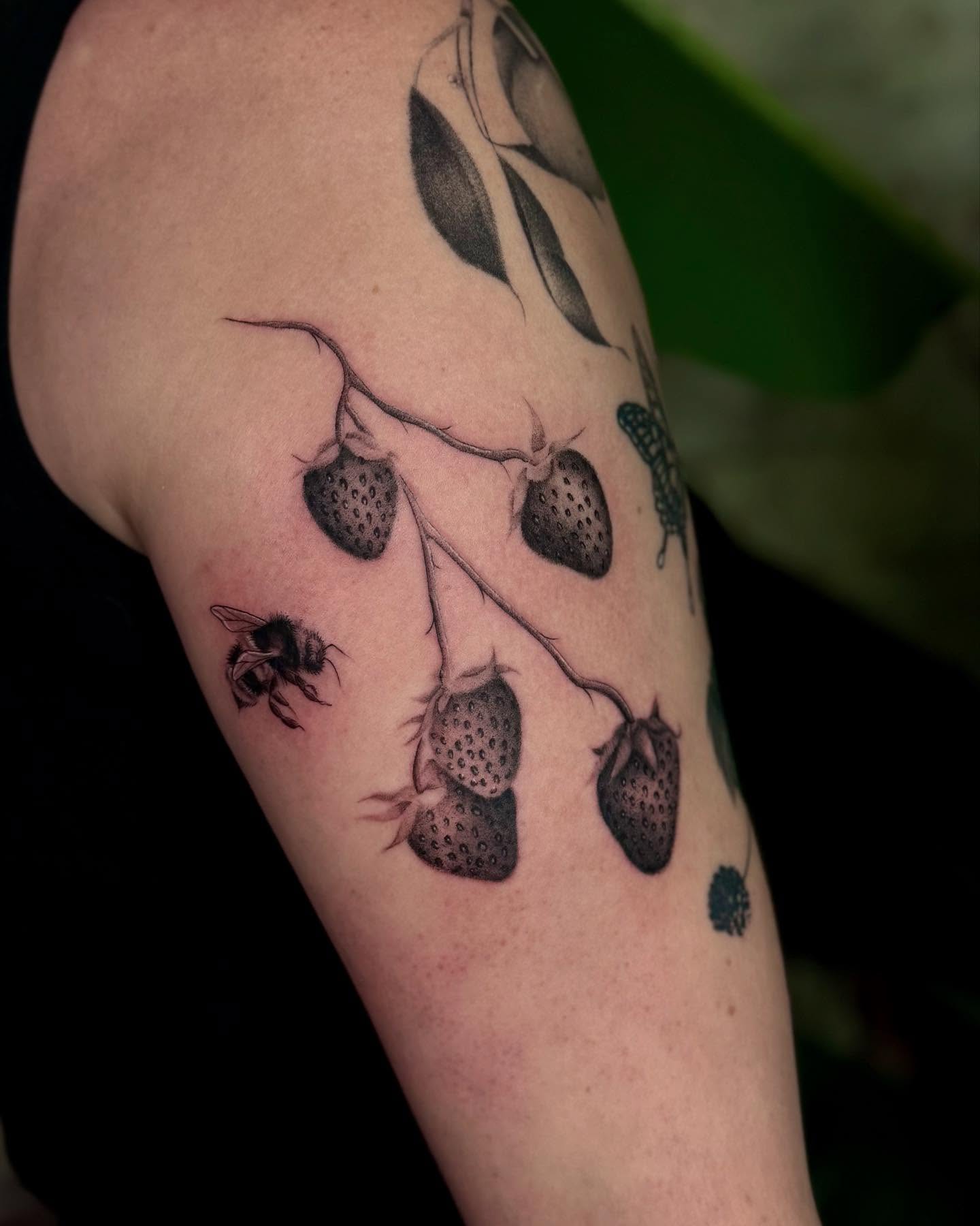 Strawberries and bee black and grey tattoo on the forearm by Isabel Smith🦋🕷️