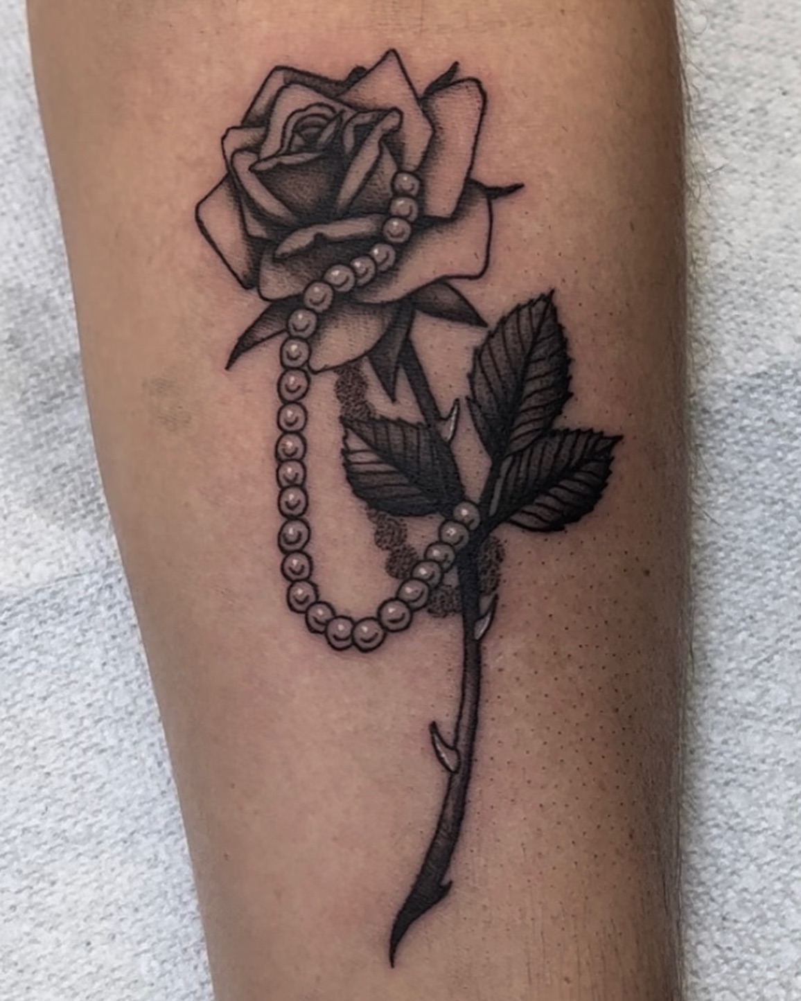 Rose with pearl necklace realism tattoo on the forearm by Cory Allen