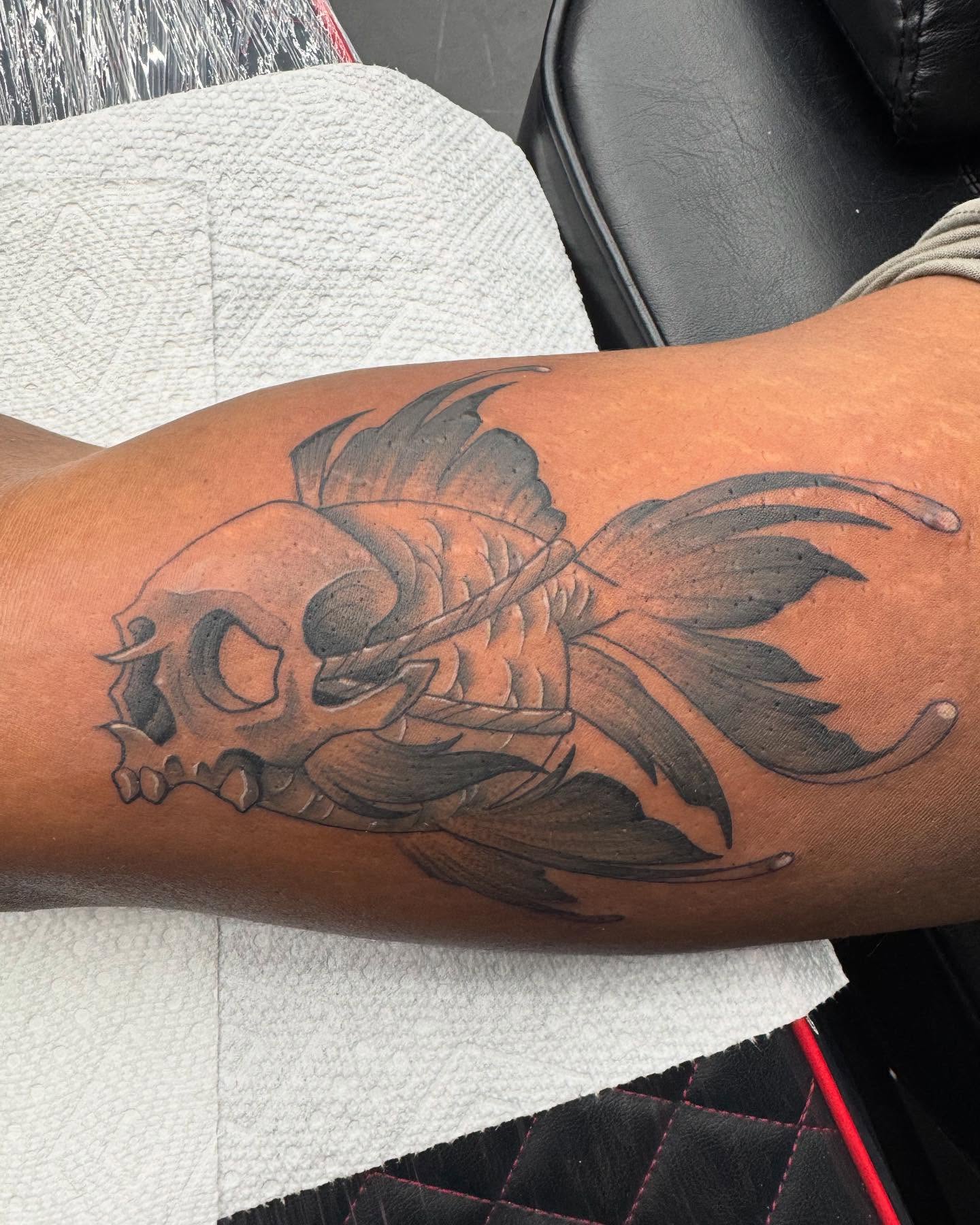 Skull and fish black and grey tattoo on the forearm by Bobby Hurst