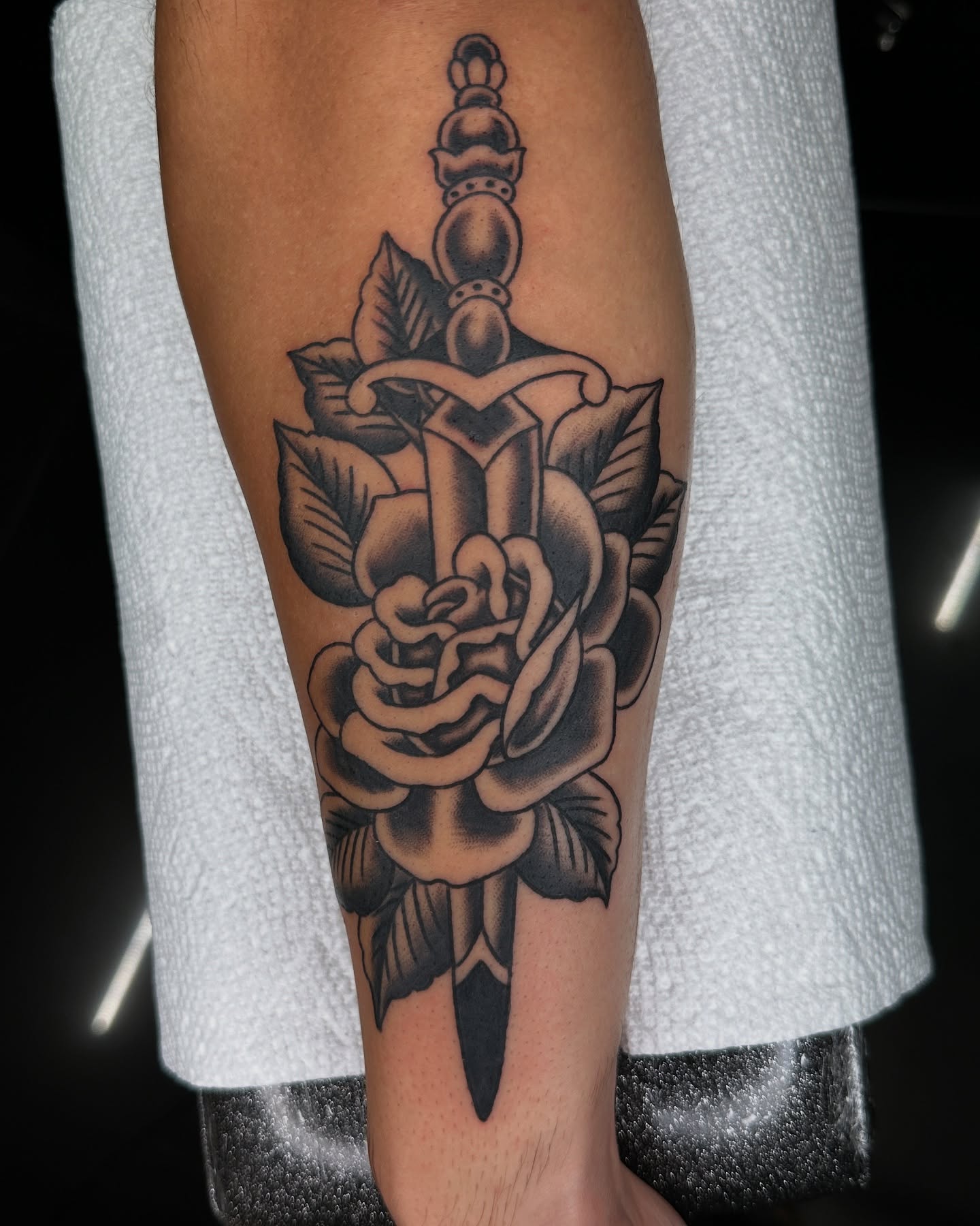 Sword and rose black and grey tattoo on the forearm by Jared, Addison, Texas