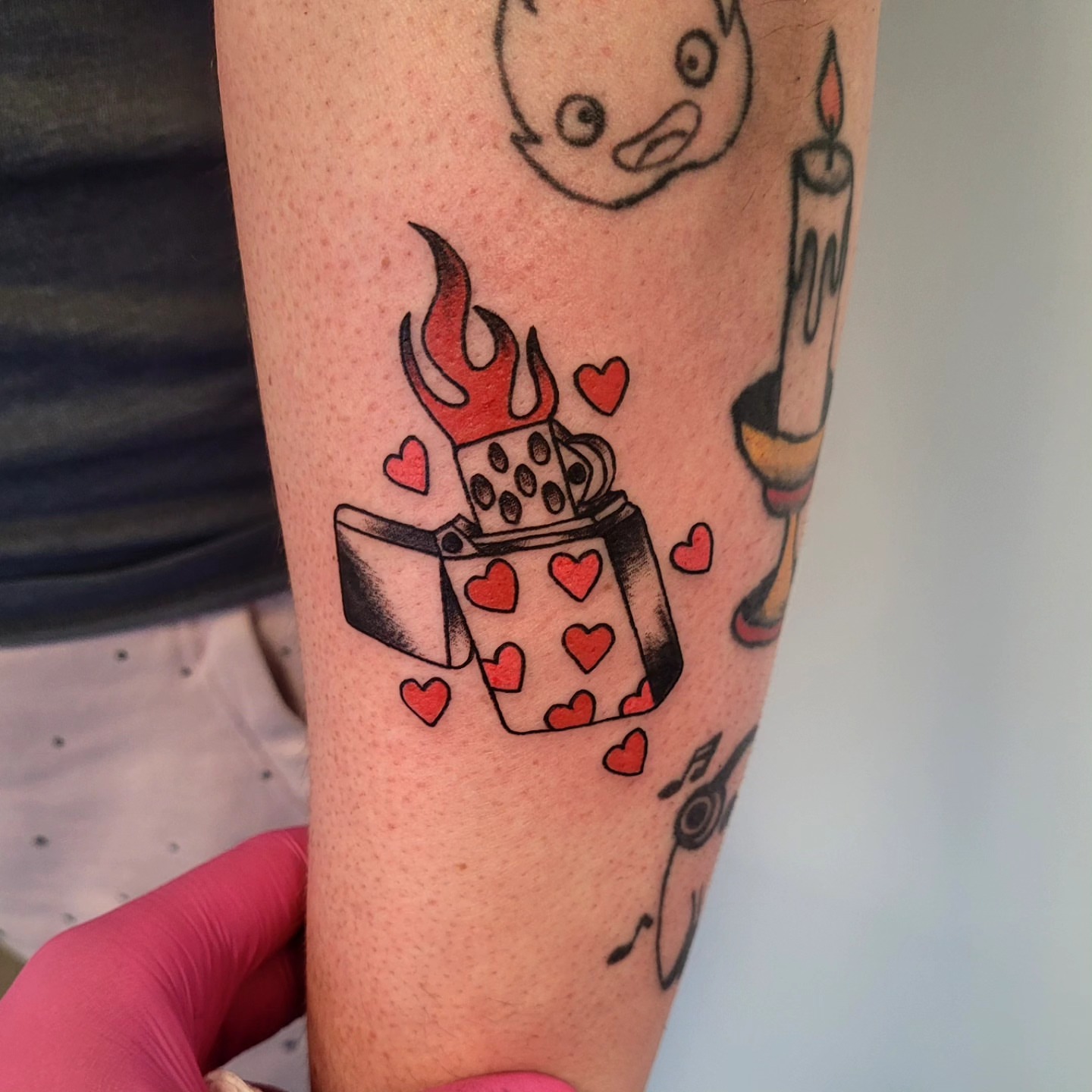 Lighter with hearts trash polka tattoo on the forearm by Wray Saulsberry