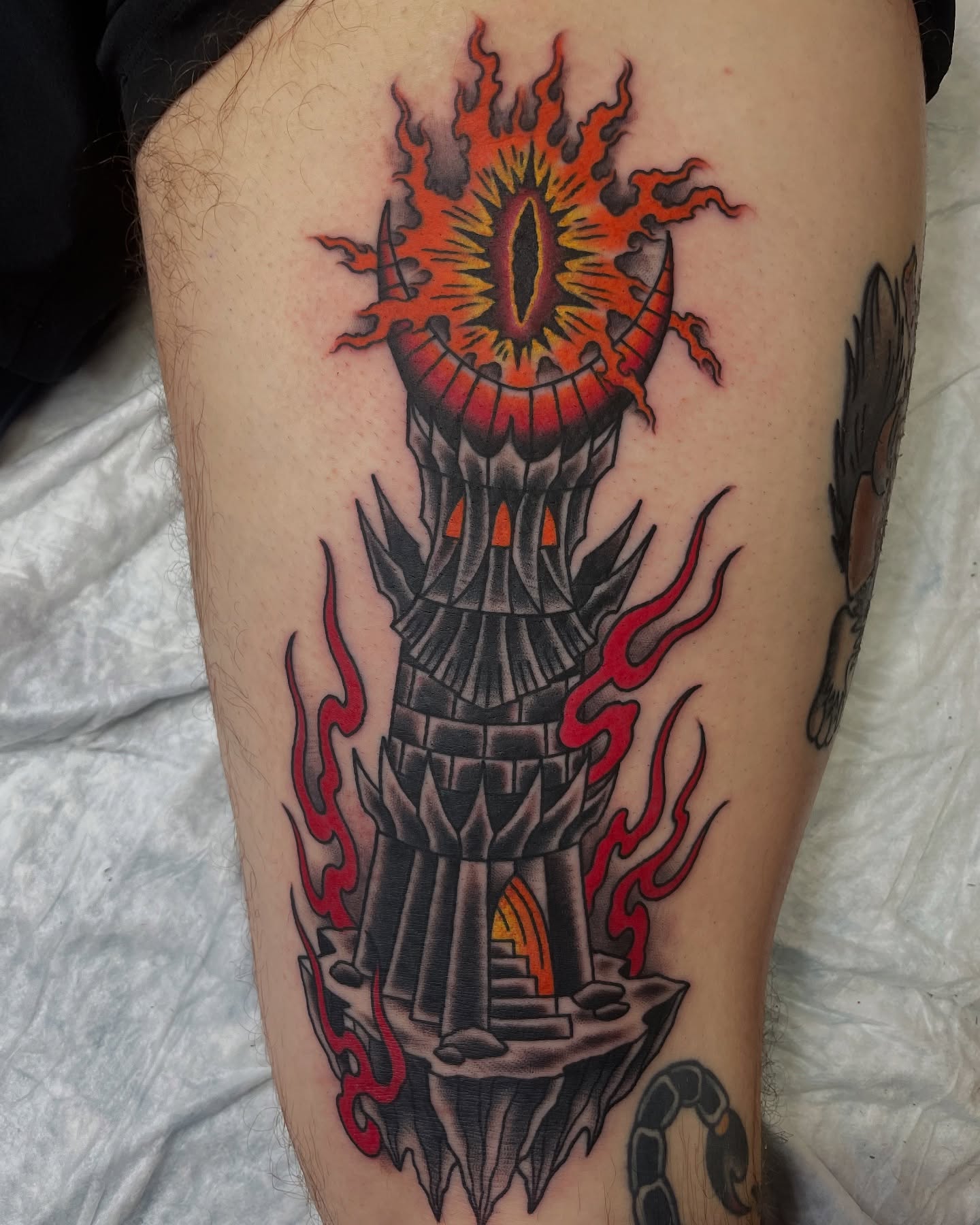 Tower with fiery eye American traditional tattoo on the thigh by Tom Taylor, Philadelphia, Pennsylvania