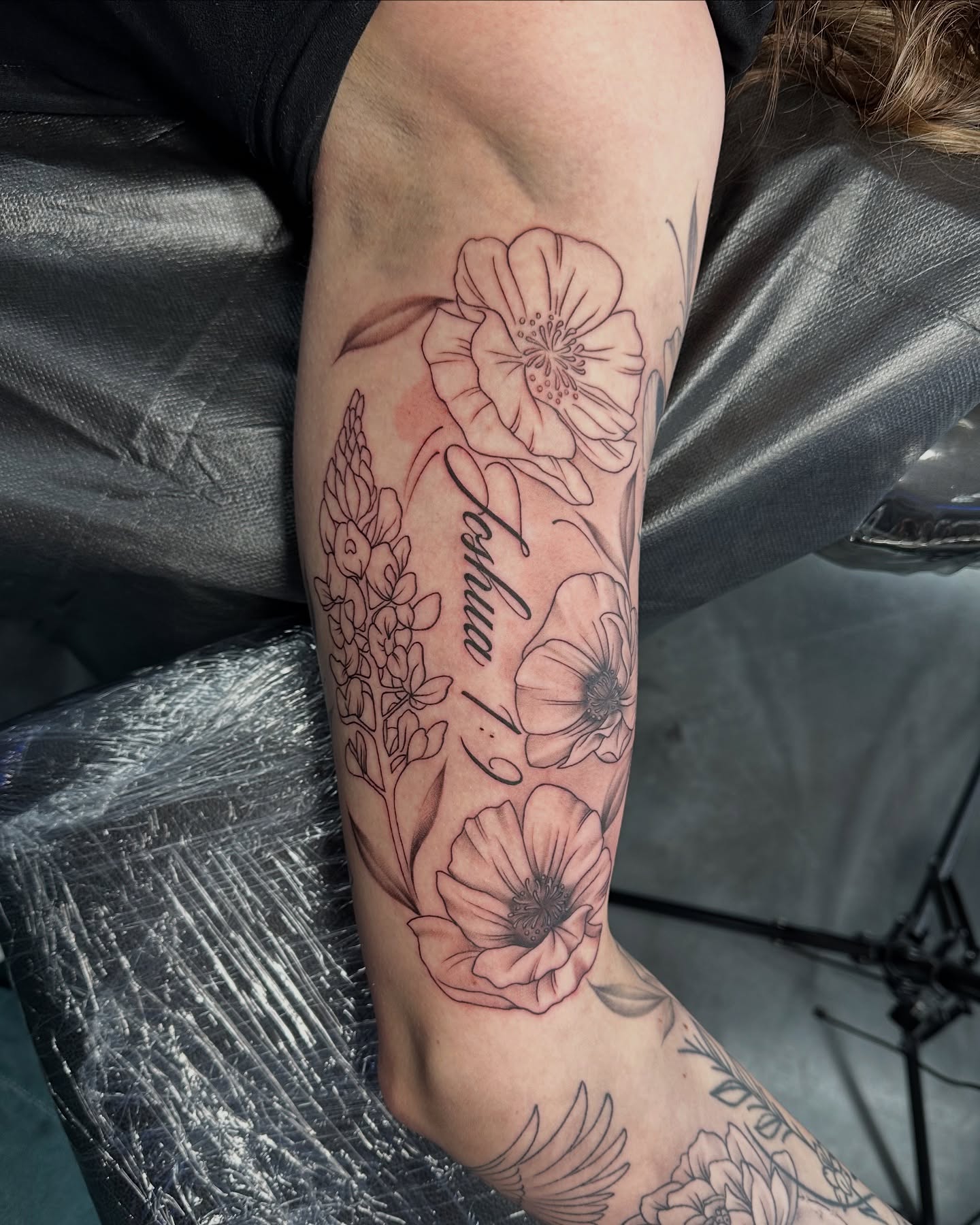 Flowers and name black and grey tattoo on the forearm by Dani B.
