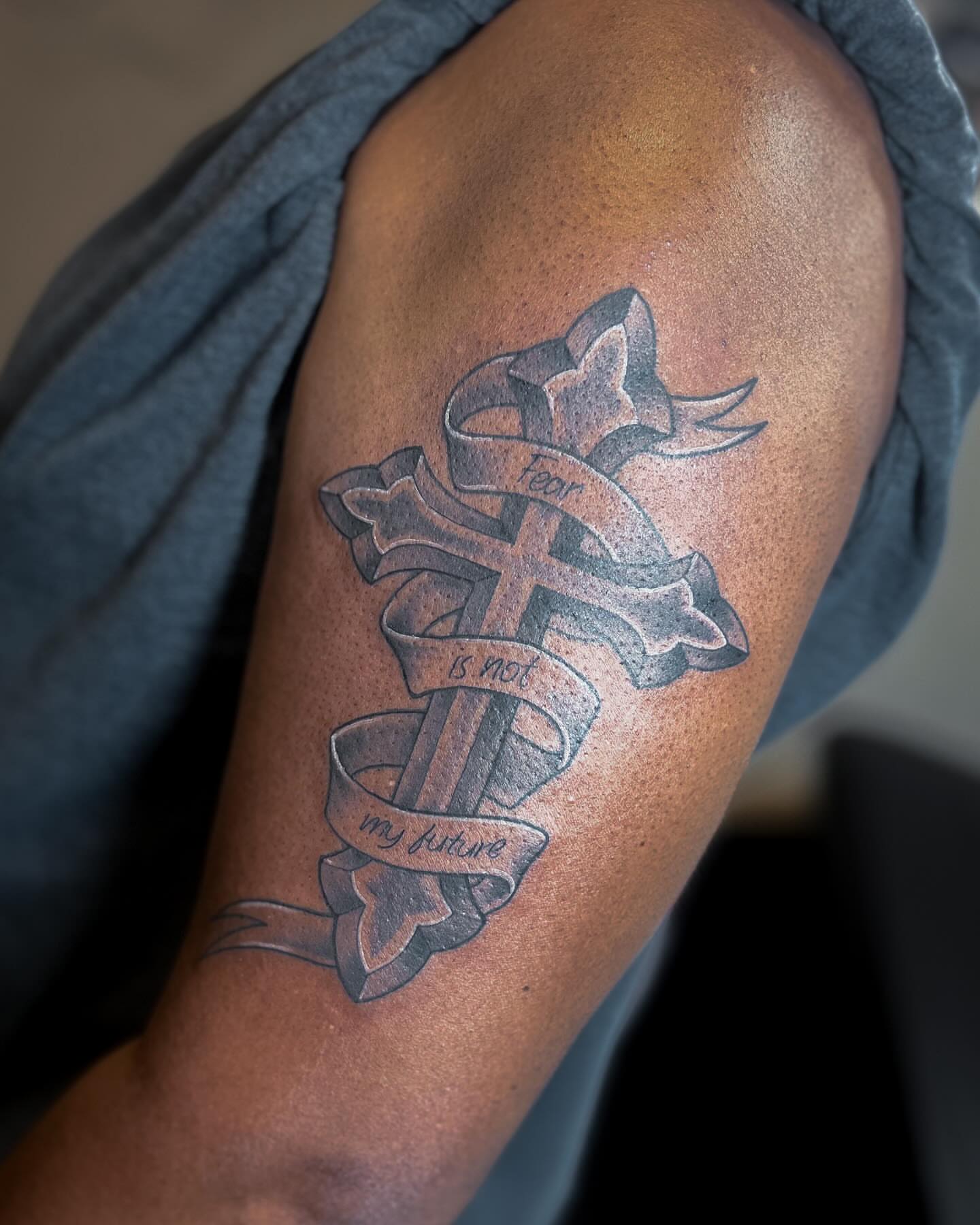 Cross with ribbon black and grey tattoo on the shoulder by Katlyne Jones