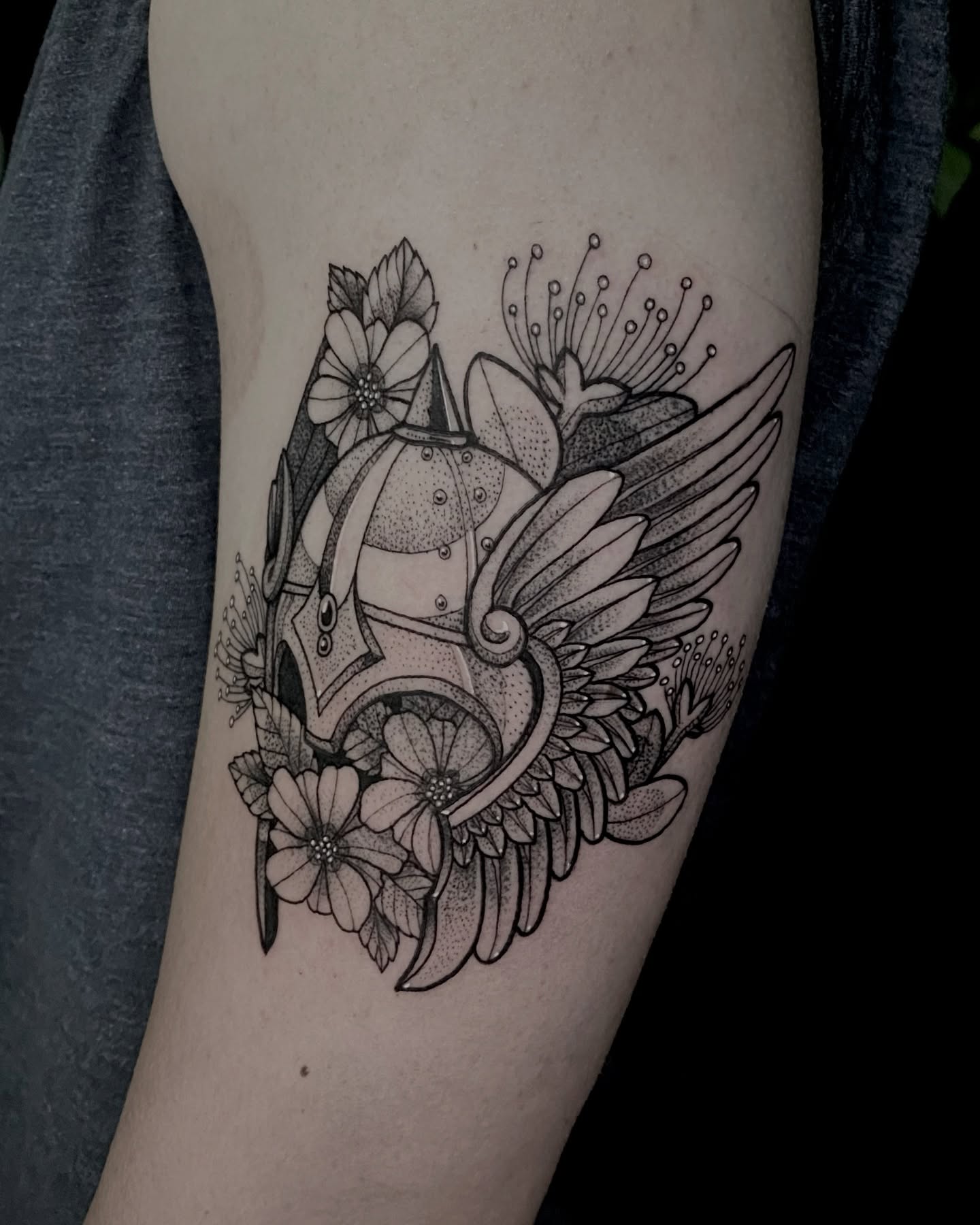 Helmet with flowers dotwork tattoo on the forearm by Rowan Starr