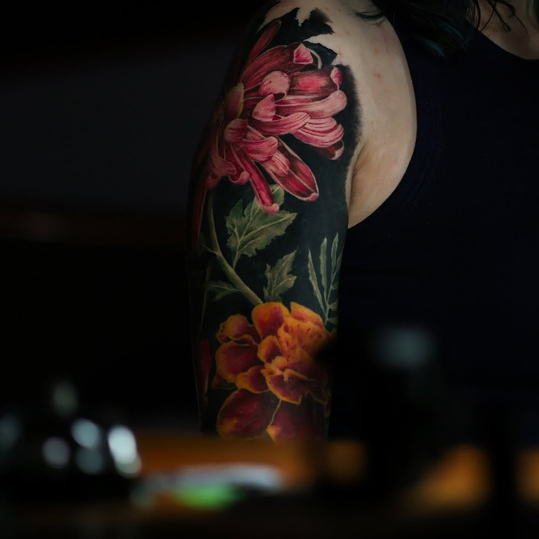 Chrysanthemum and marigold flowers Japanese tattoo on the upper arm by Felipe Andrade