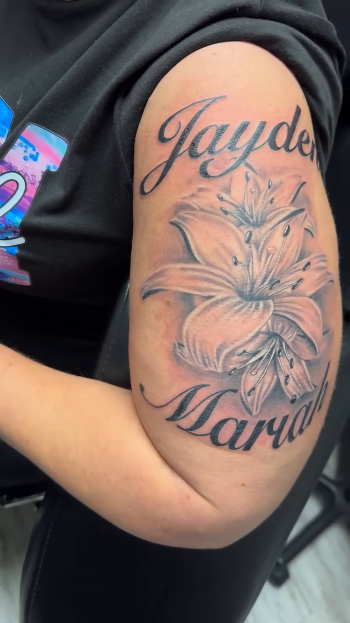 Lily with names Jayden and Mariah fine line tattoo on the upper arm by Luis Cabrera, Cleveland, Ohio