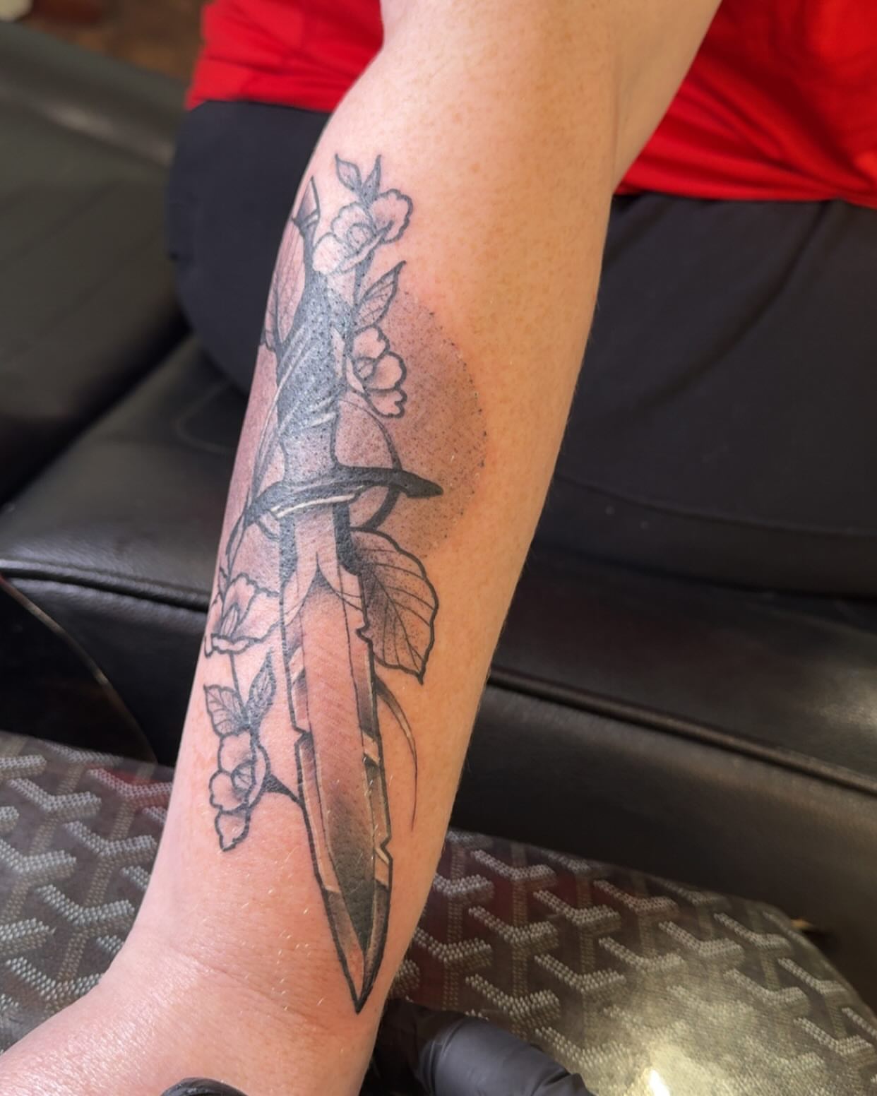Sword and flowers black and grey tattoo on the forearm by Robbie Roberson
