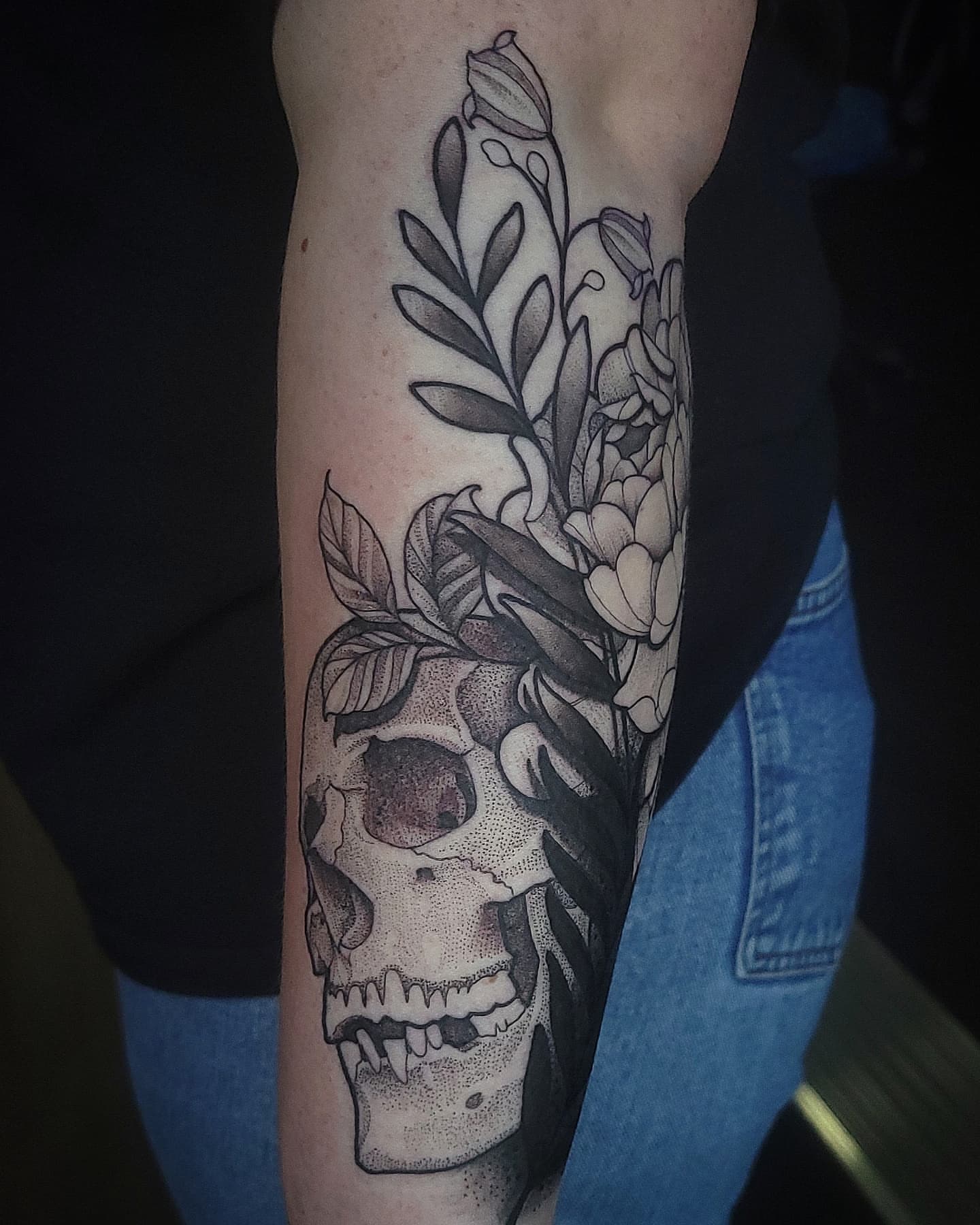 Skull and flowers dotwork tattoo on the forearm by Sean Hollinger