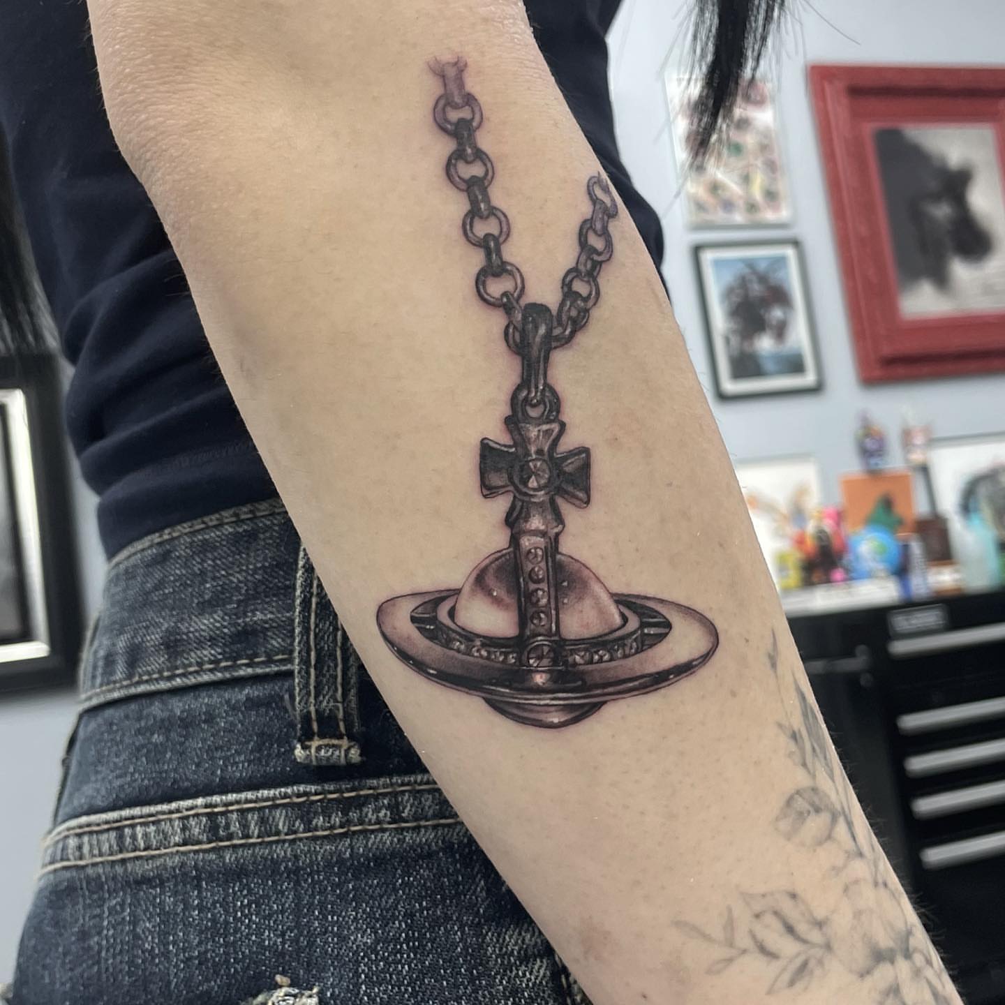 Cross and planet black and grey tattoo on the forearm by Austin Jones