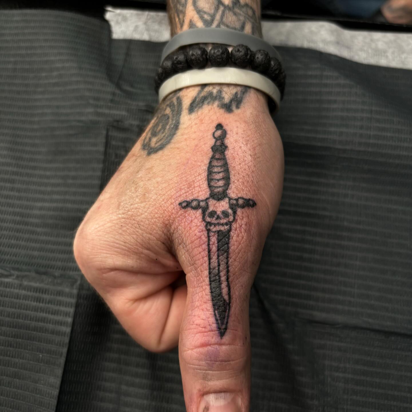 Dagger black and grey tattoo on the hand by Brett Ferguson