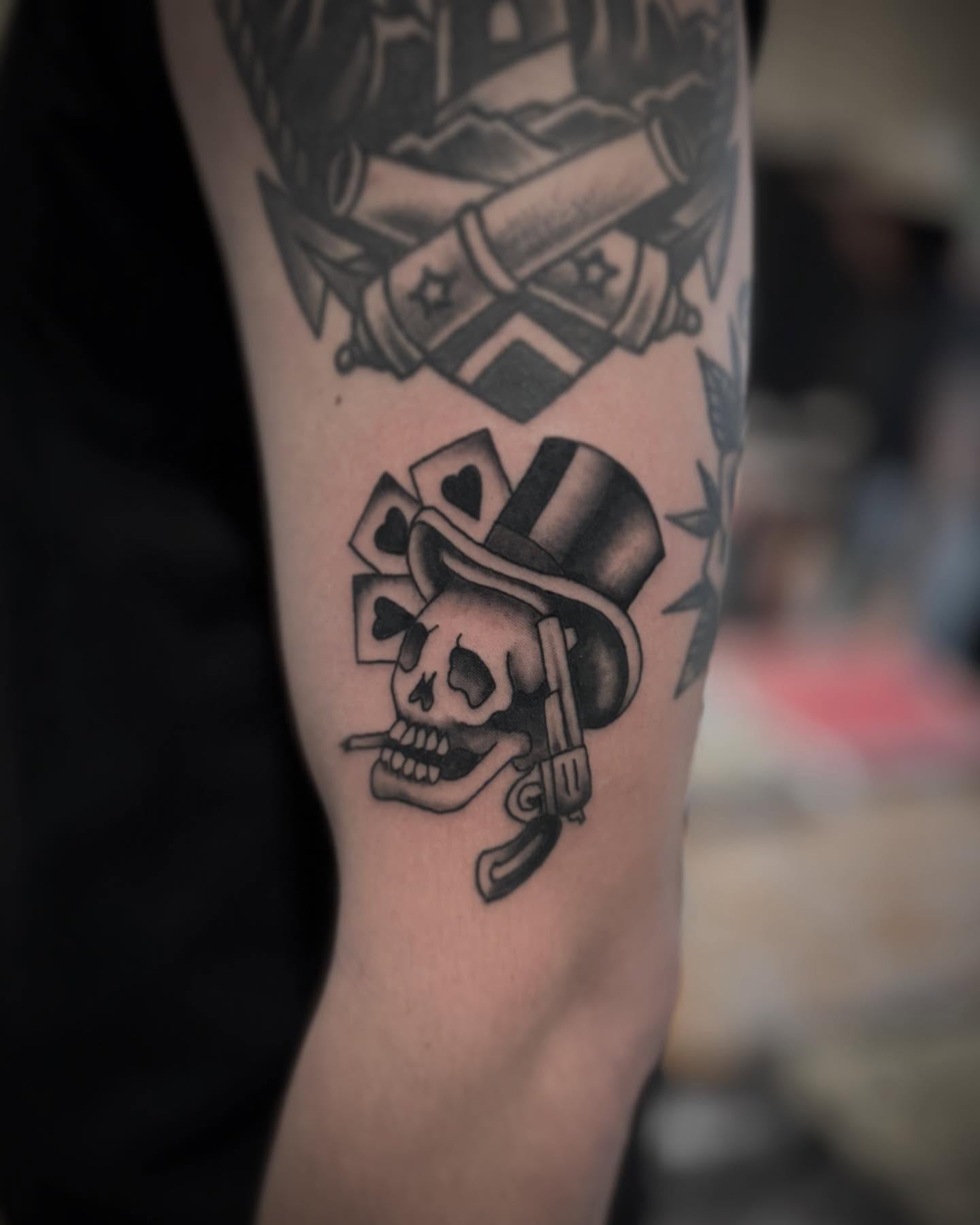 Skull with top hat and cards American traditional tattoo on the forearm by Micah Norman, San Francisco, California