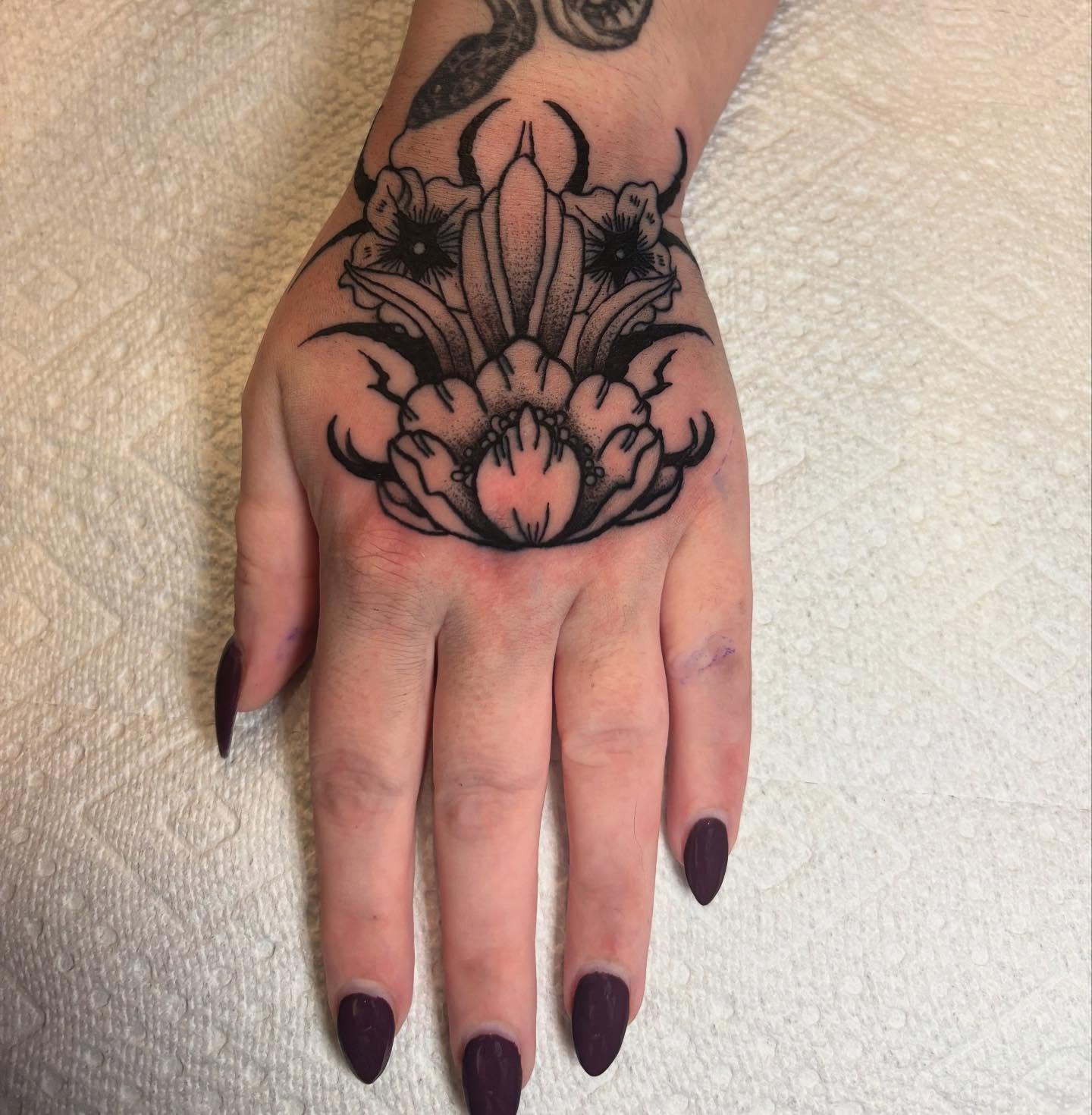 Floral arrangement black and grey tattoo on the hand by Bryan Black