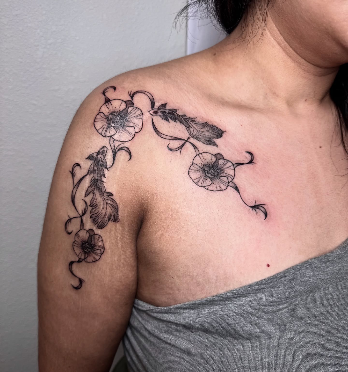 Flowers and feathers black and grey tattoo on the shoulder by Jess