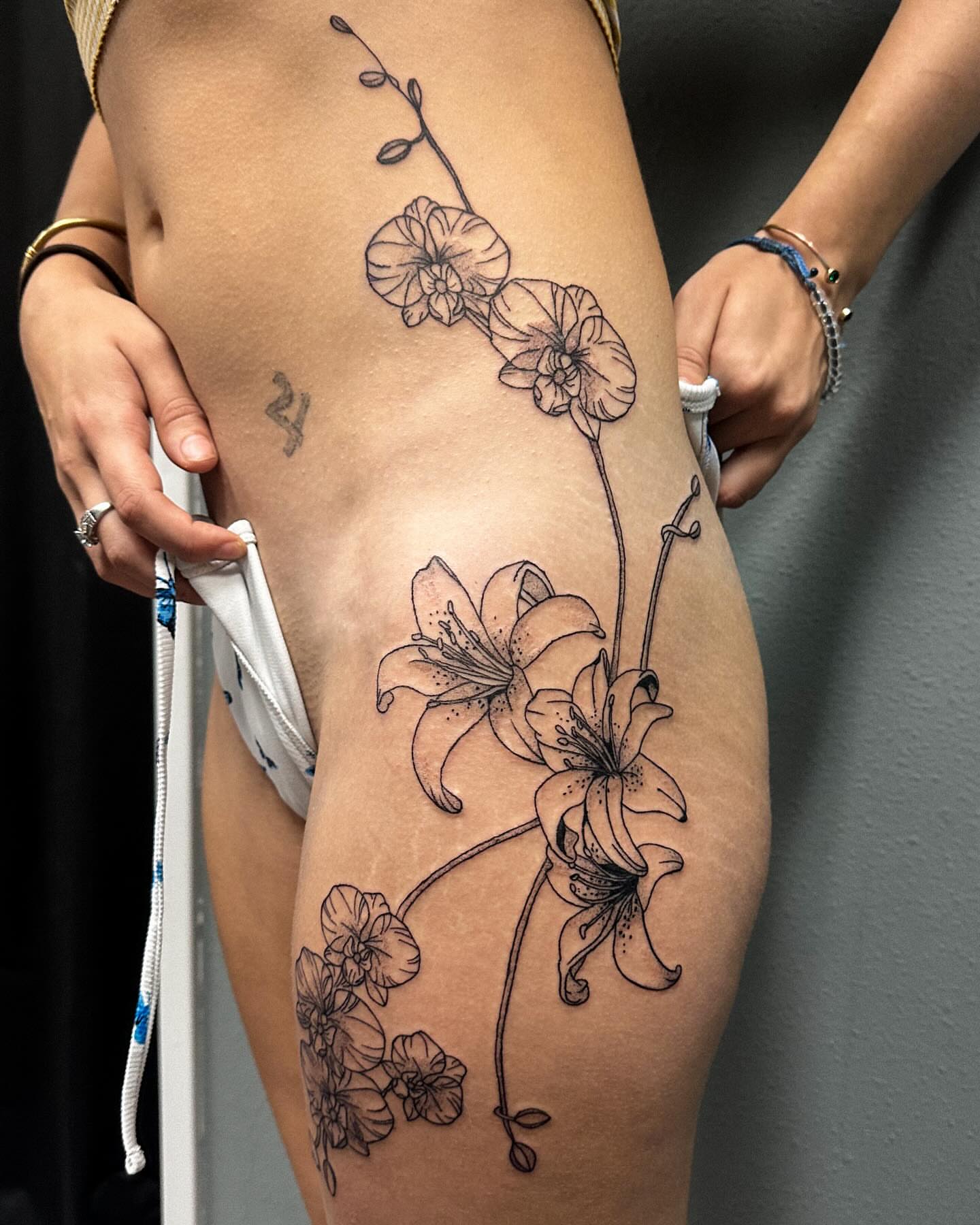 Lilies and orchids black and grey tattoo on the thigh by Portland Tattoo Artist