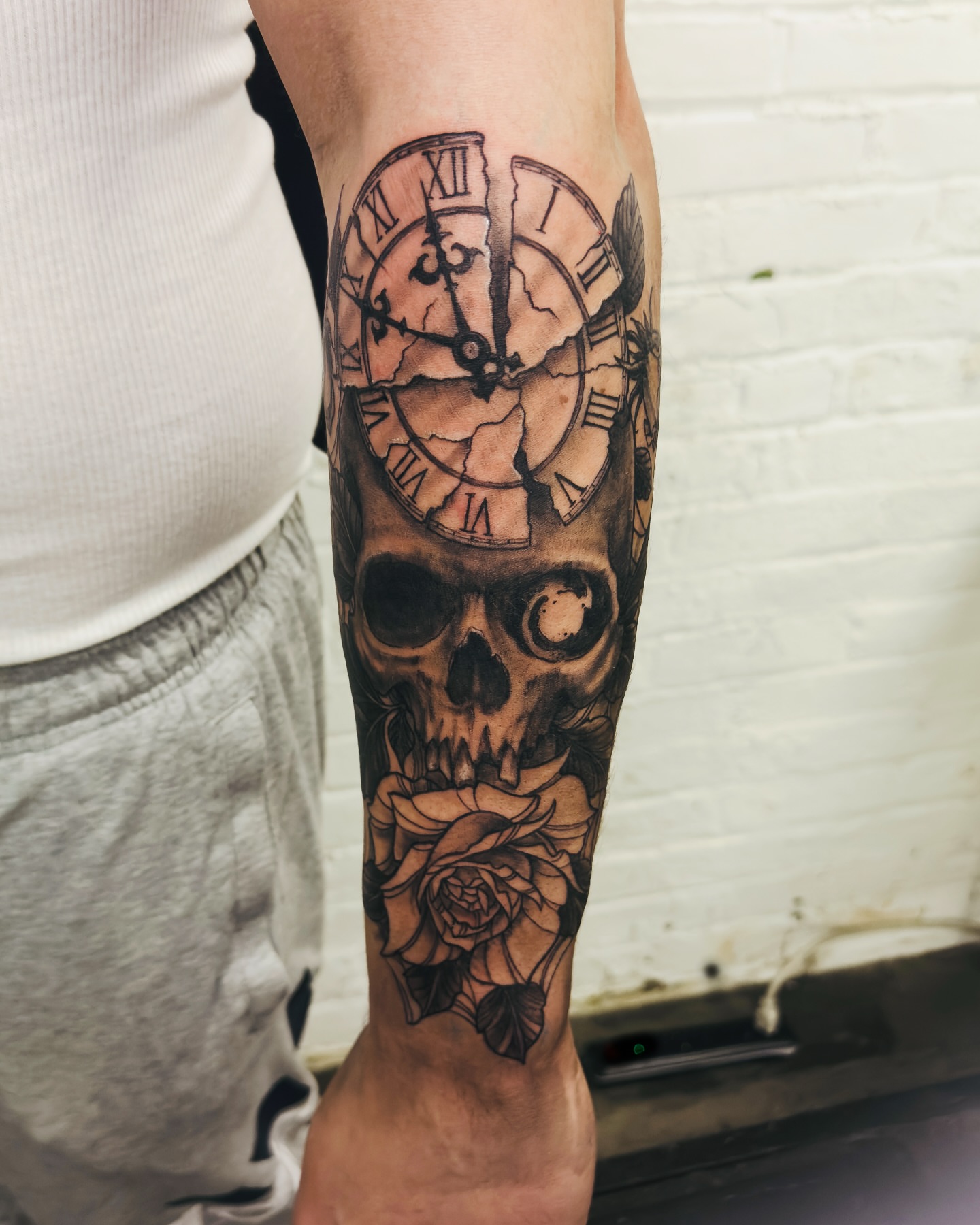Skull with clock and rose realism tattoo on the forearm by Jeff Brock