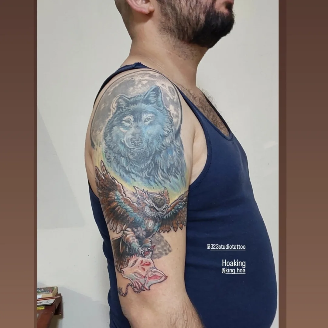 Wolf and eagle realism tattoo on the upper arm by Hoa King