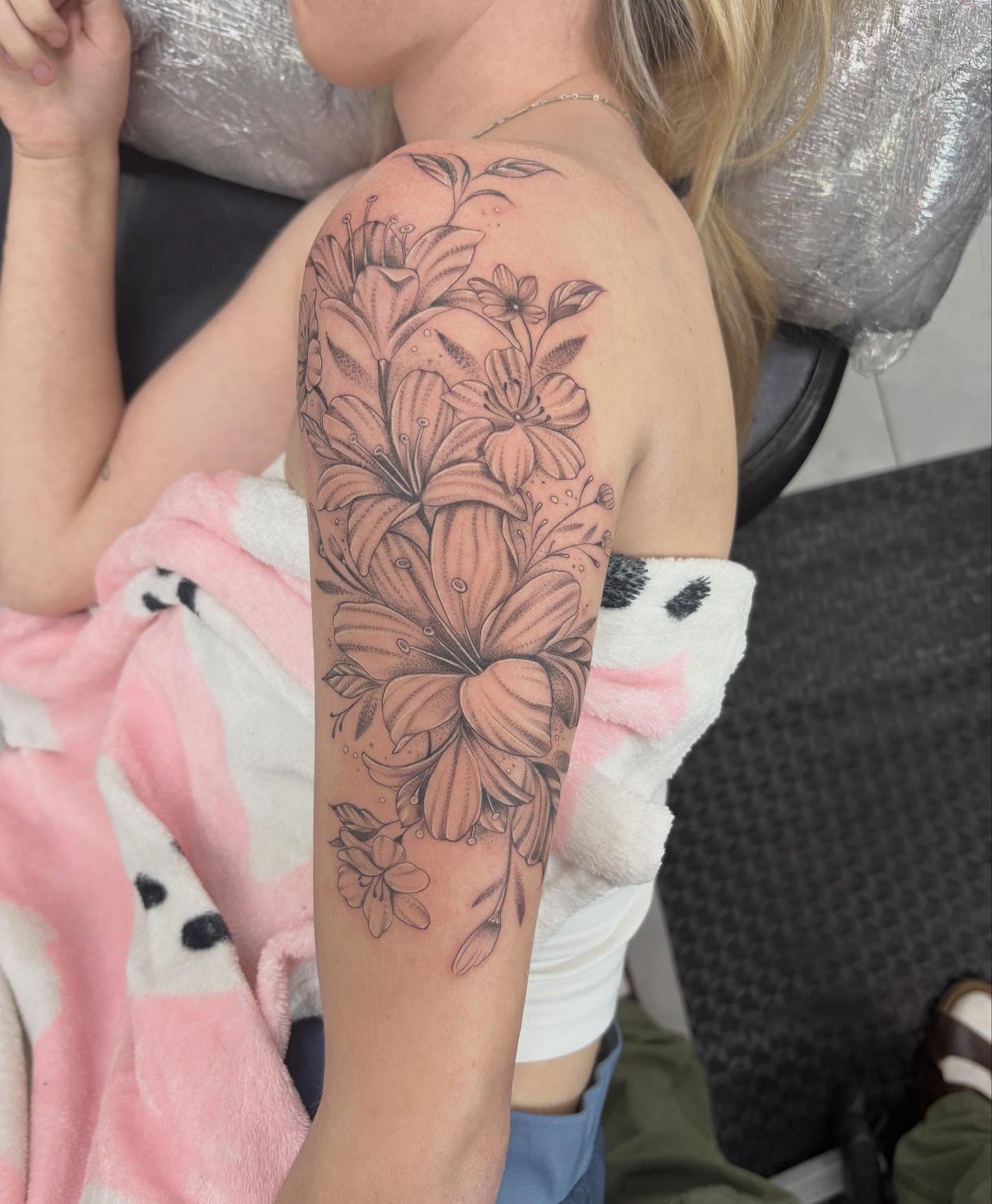 Lilies black and grey tattoo on the upper arm by James Howell