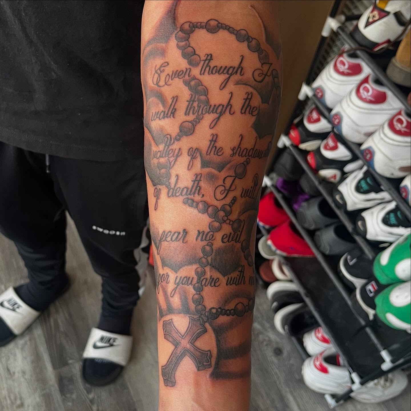 Rosary and scripture black and grey tattoo on the forearm by Bris