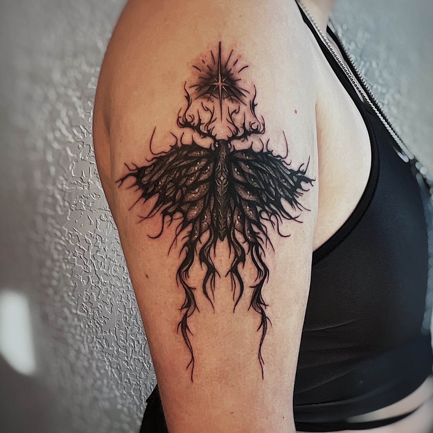 Root system black and grey tattoo on the upper arm by Nikki Ward