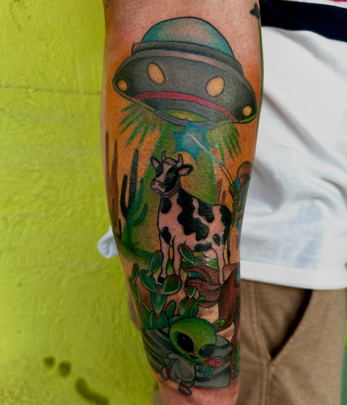 Cow abduction illustrative tattoo on the forearm by Holle Hellfire
