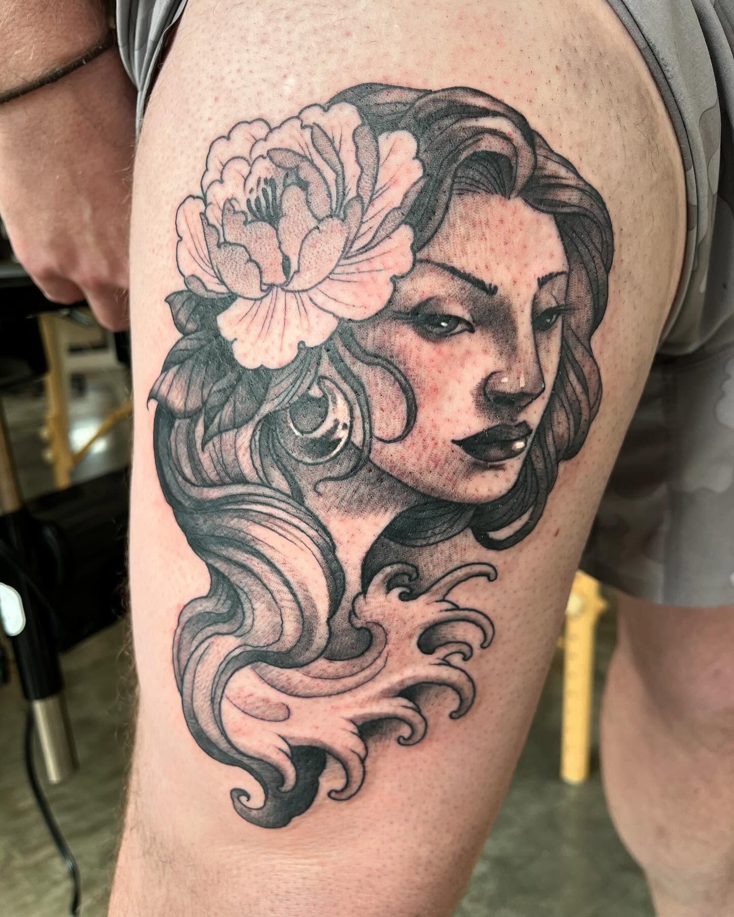 Woman with flower black and grey tattoo on the thigh by Ian White