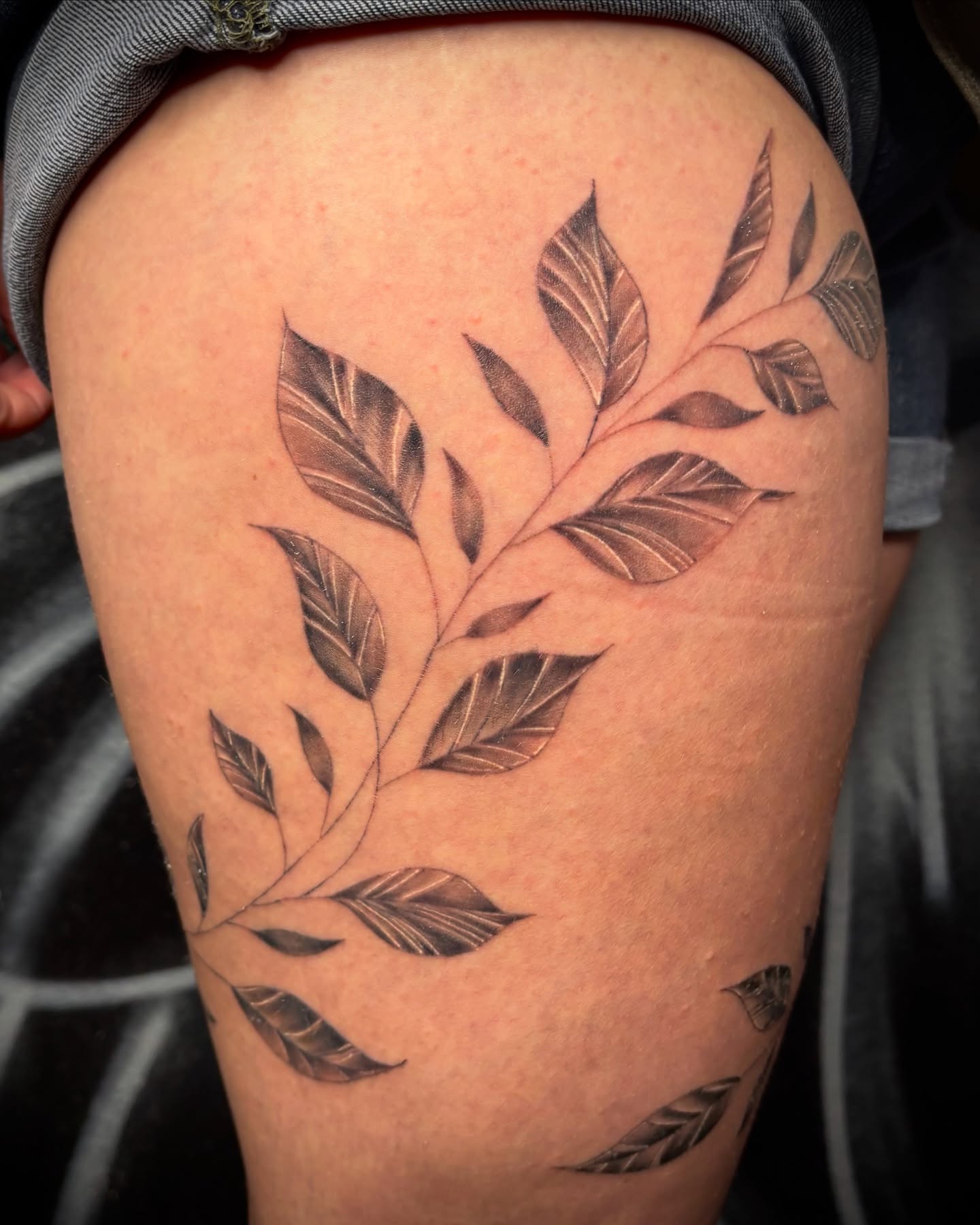 Branch with leaves black and grey tattoo on the thigh by Las Vegas Tattoo Artist