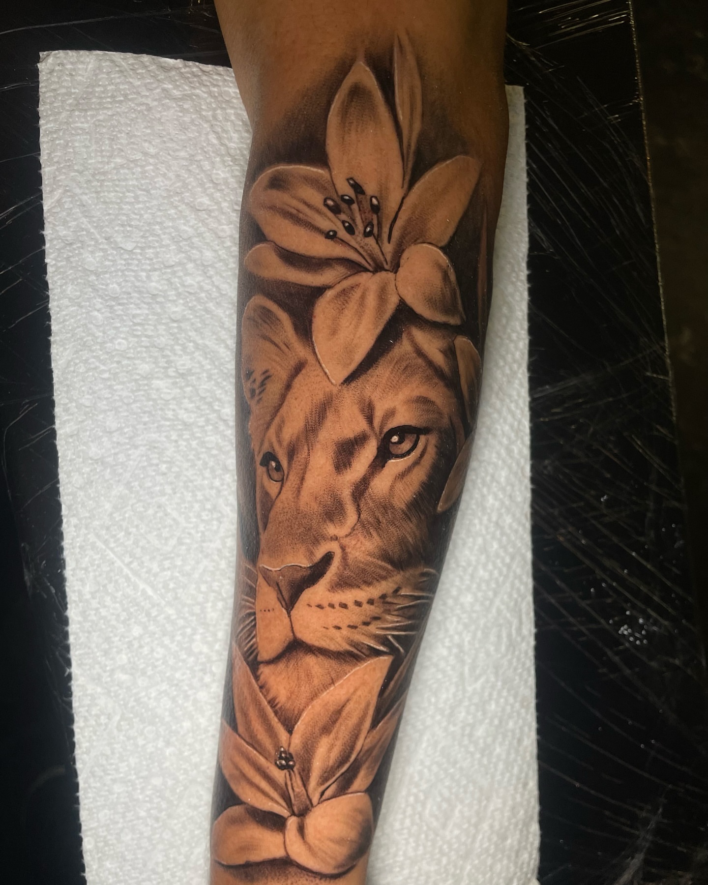 Lion with lily realism tattoo on the forearm by Vic